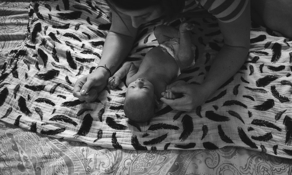 mother admiring her newborn child on bed; black and white