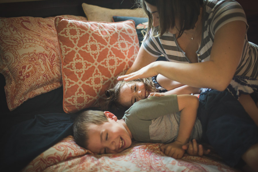 mother ticking children on bed in laughter and joy