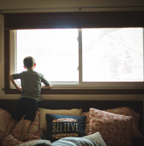 boy peeking outside of large window, reflecting 