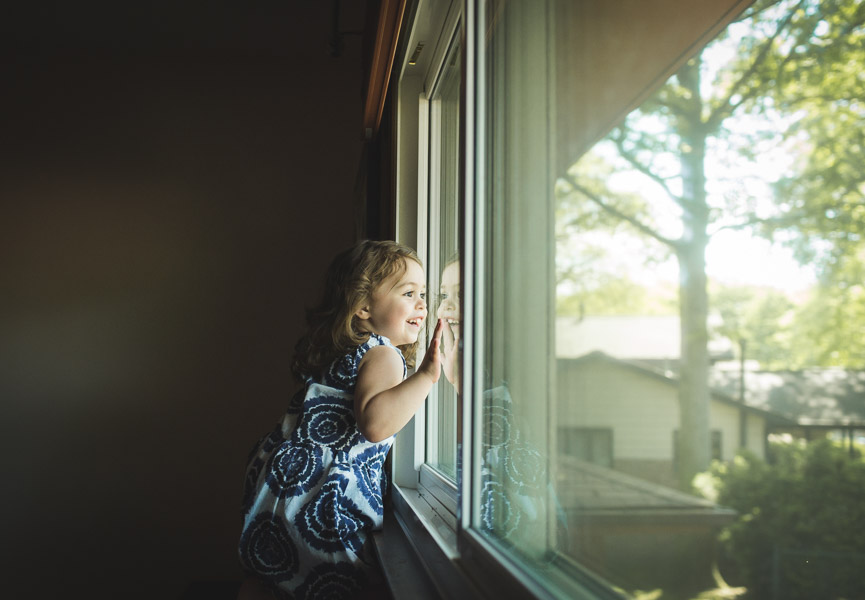 little girl looking out window with face pressed against the glass, wonder