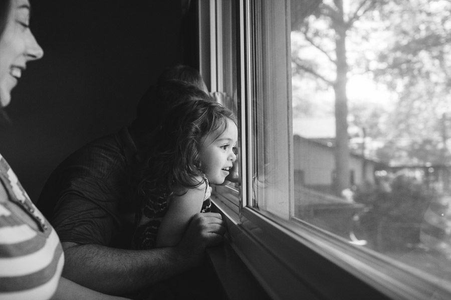 little girl looking out window with mother; black and white