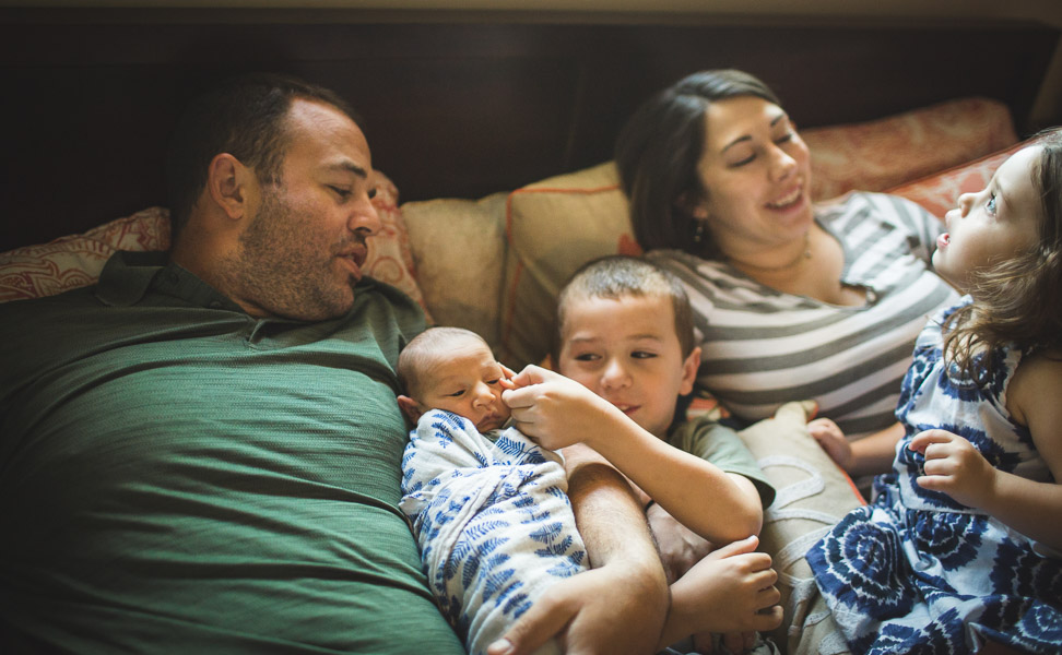 Family snuggles, connecting on bed in soft window light 