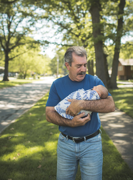 grandfather holding granddaughter in morning light of neighborhood 