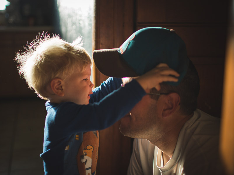 father and son connecting through loving play with hat