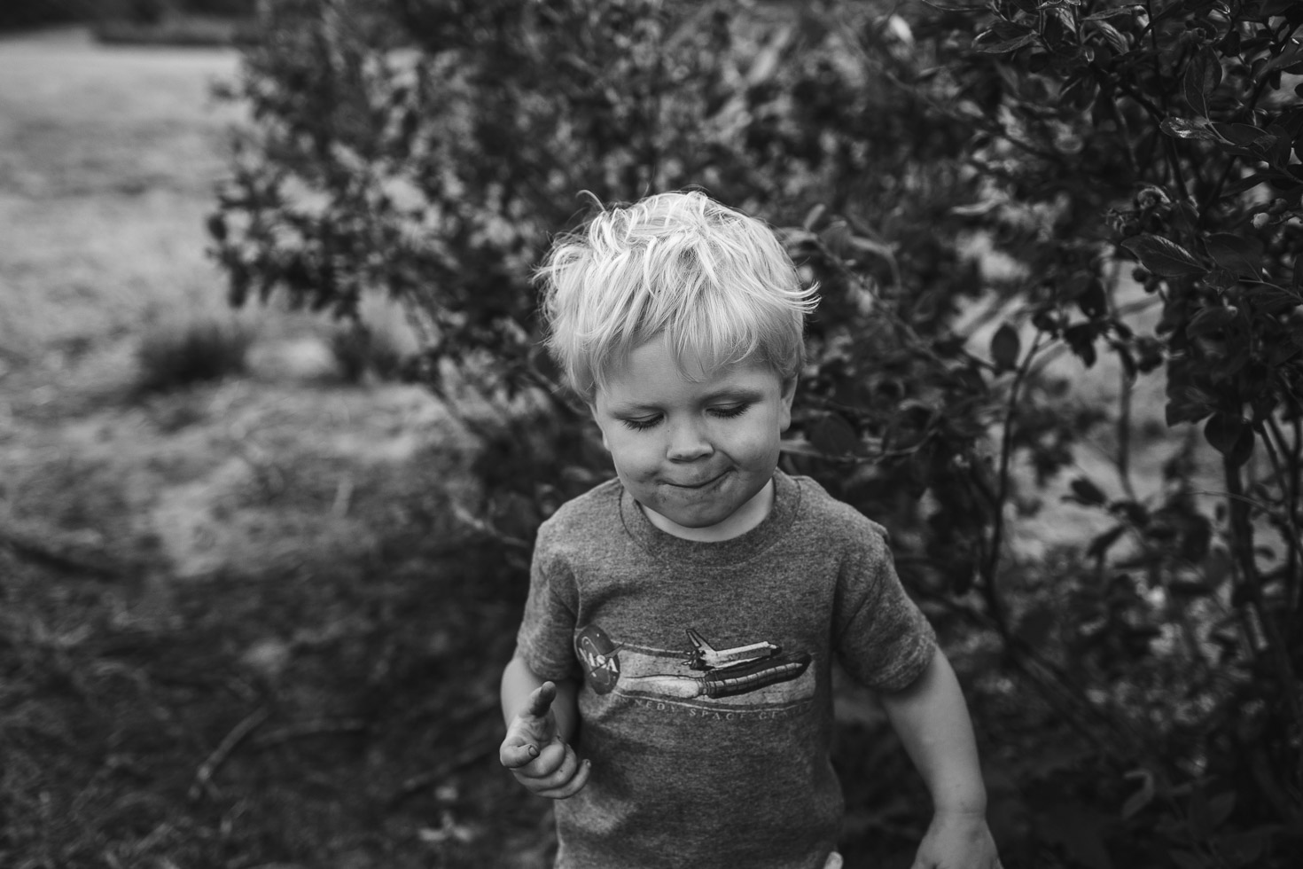 toddler boy joyful with full mouth and belly of blueberries