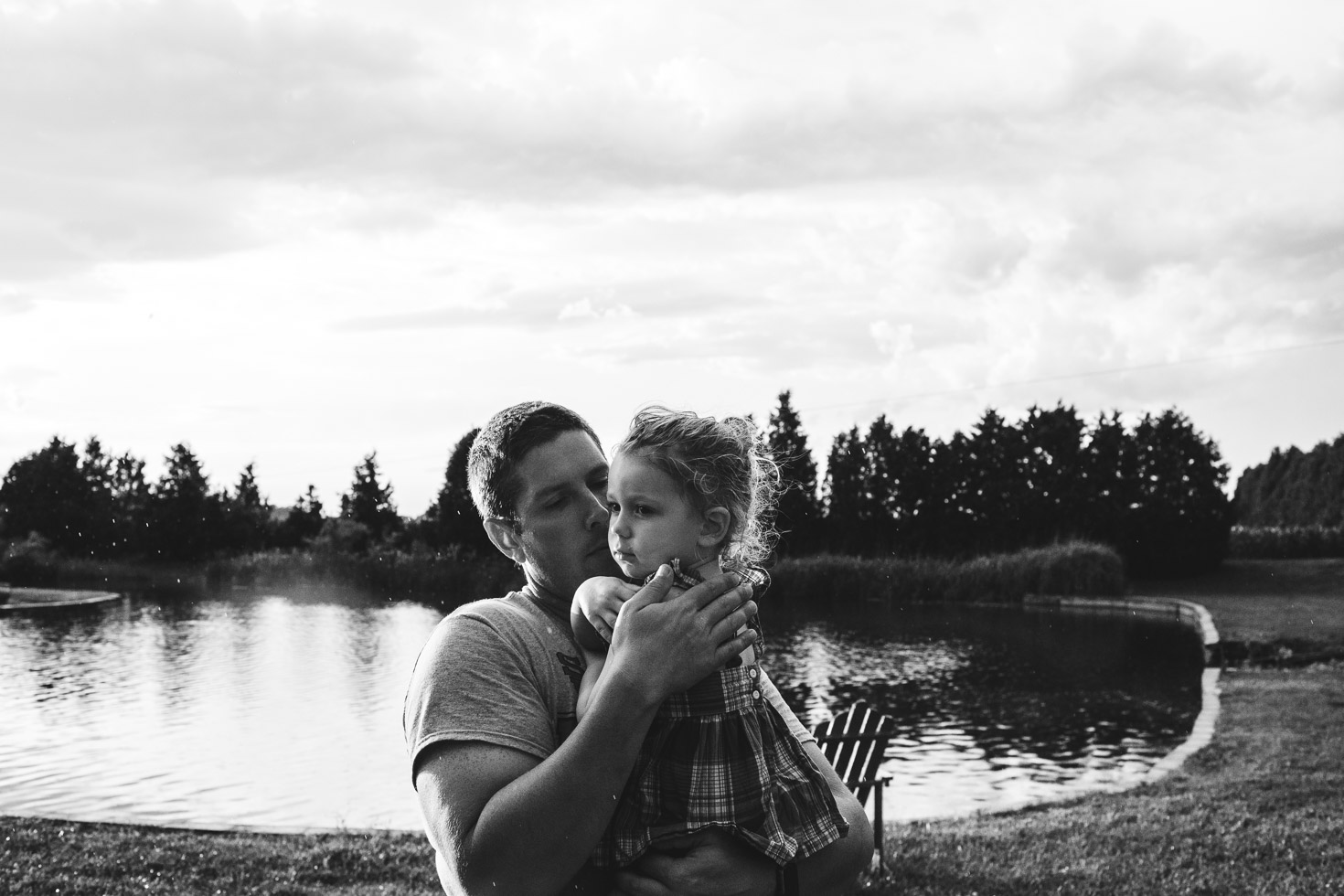 Father embracing daughter, country field in front of lake, connection, powerful black and white 