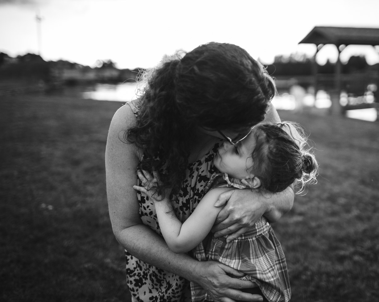 grandmother embracing child, warm connection, loving, powerful black and white in field by pond