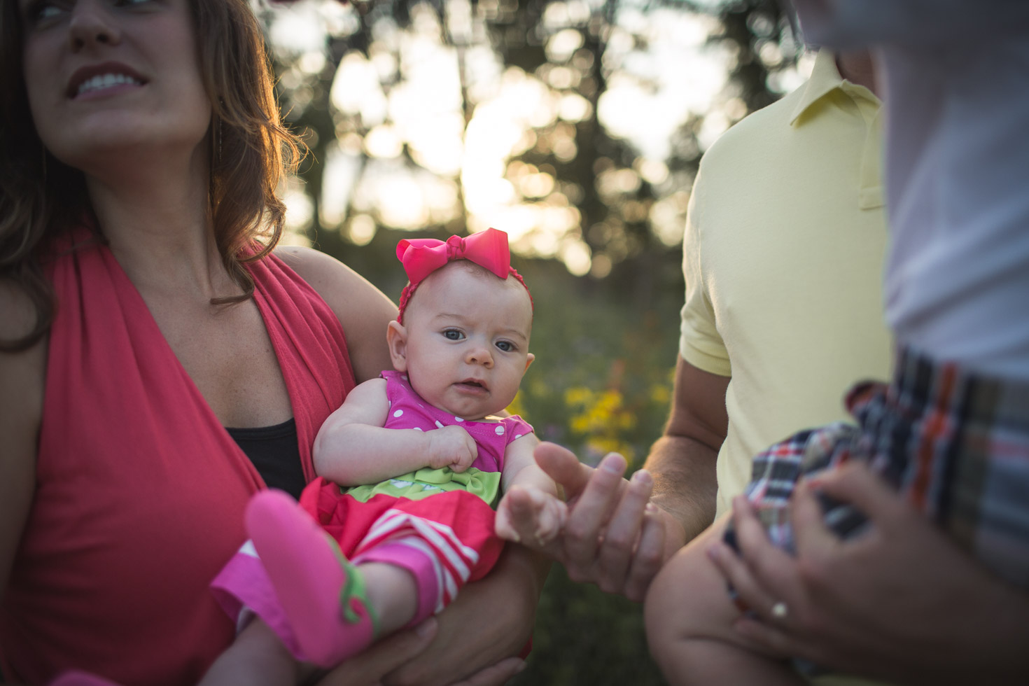 Family image with focus on infant looking at camera while being held in mothers arms 