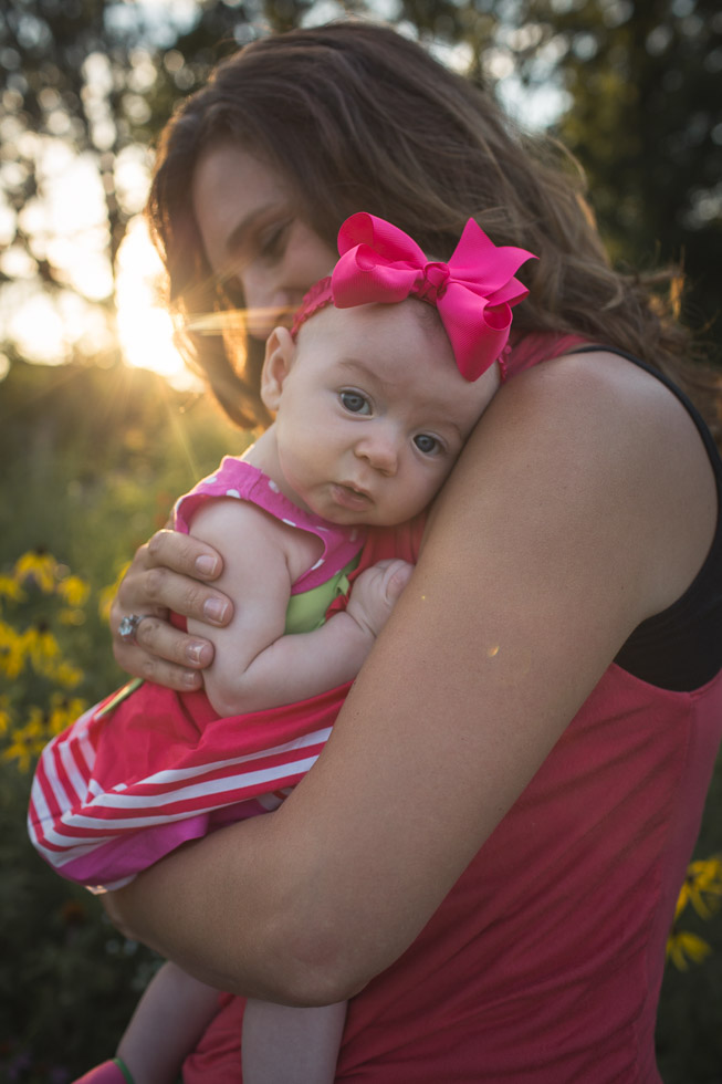 Mother cradling daughter on arm, with golden backlight streaming in, powerful connection