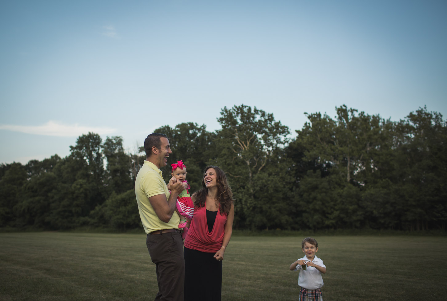 Family laughing together in wide open field, connection, embrace