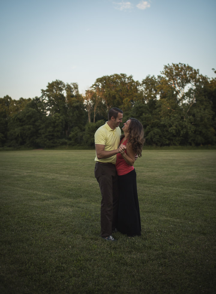 couple in warm embrace in wide open field, sunset 