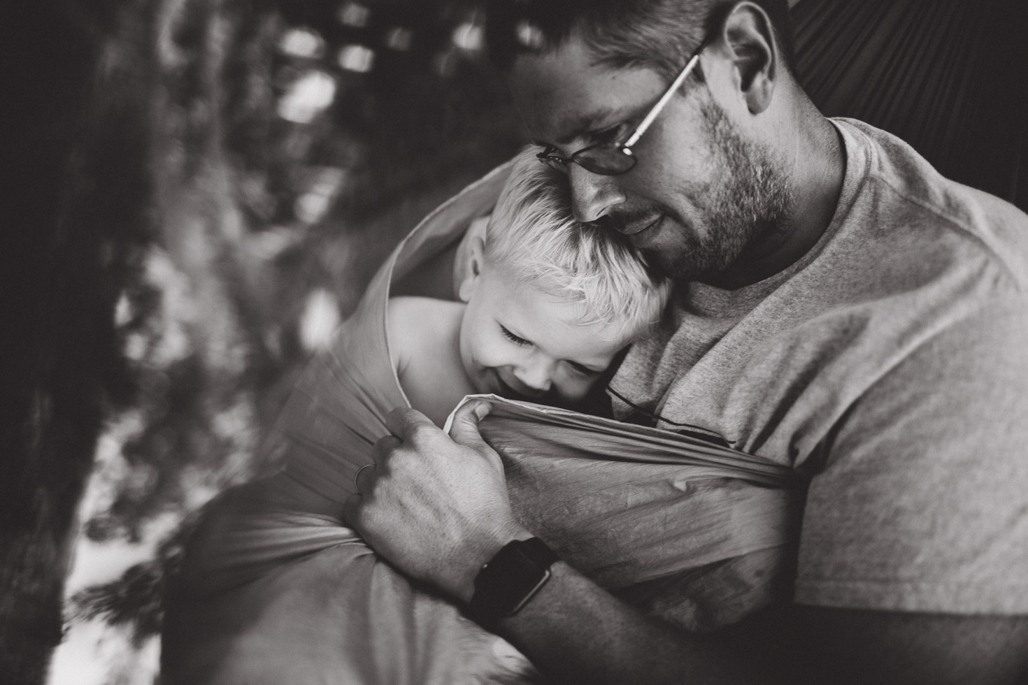 Father embracing son in loving connection in hammock; black and white portrait 