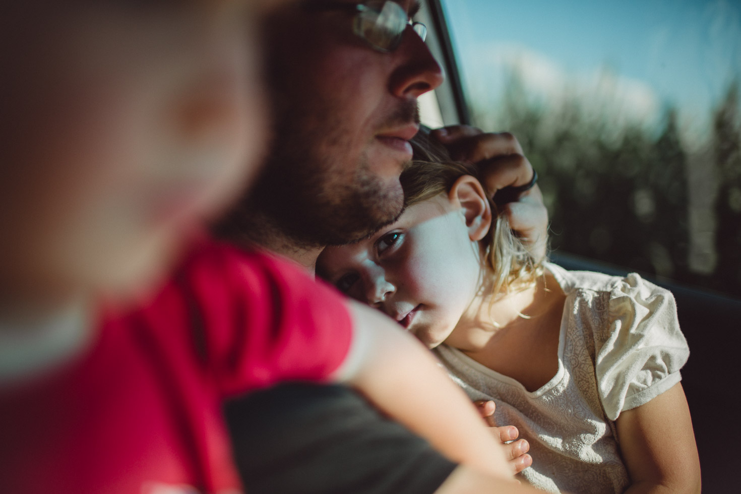 Daughter held in her father's arms in car, shadow light play, connection