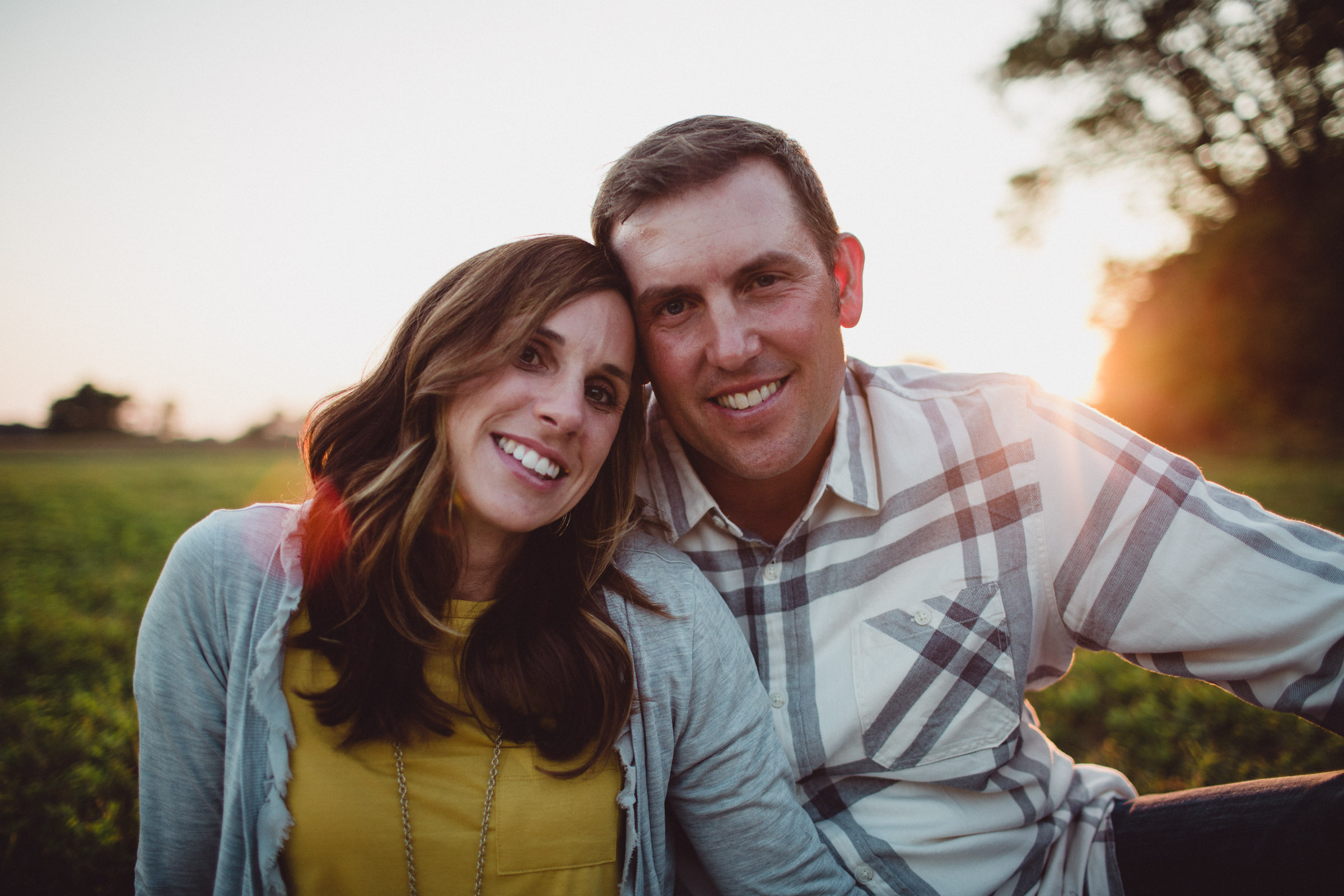 portrait of husband and wife with faces touching in sun flare 