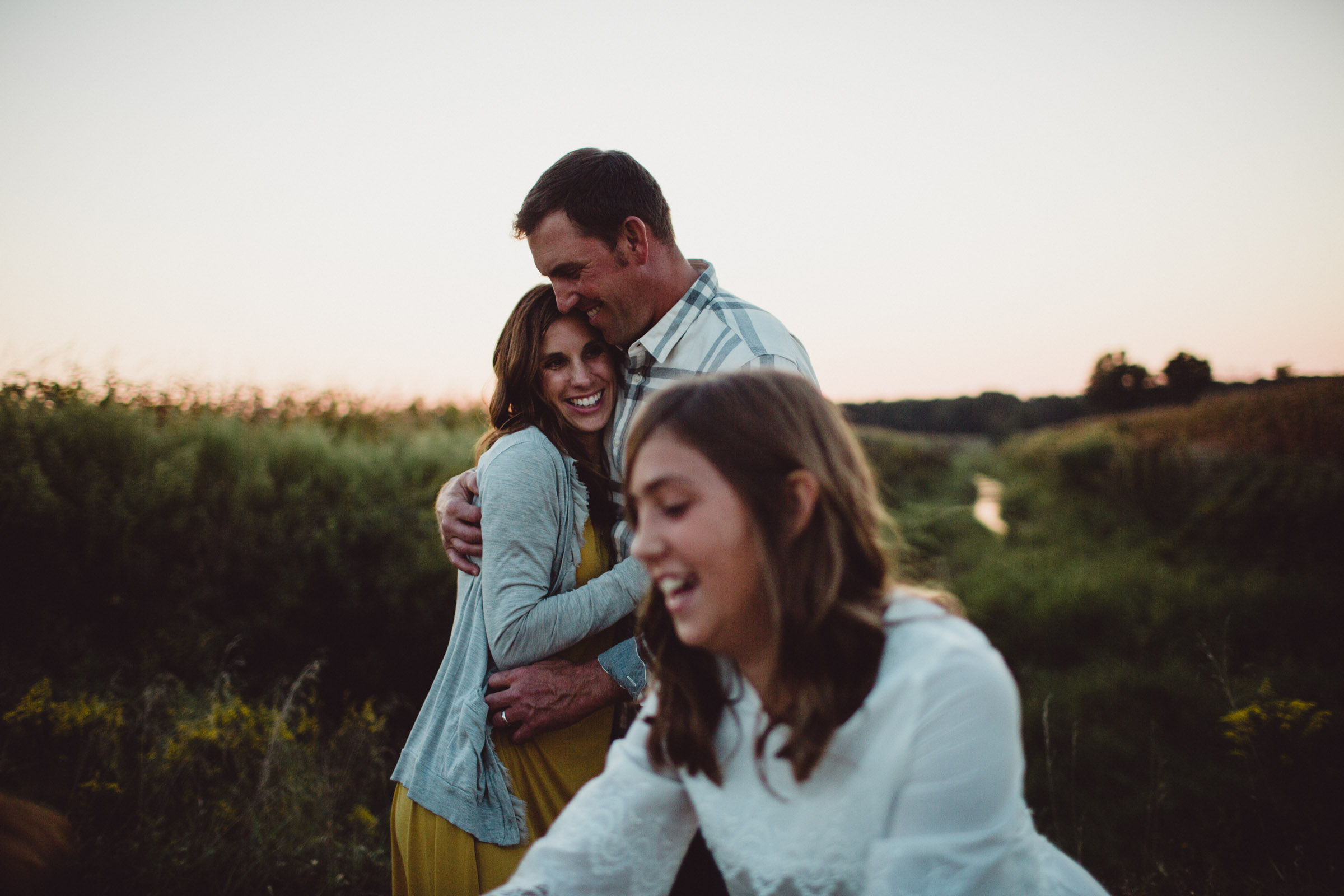 parents hugging and daughter dancing in the foreground 