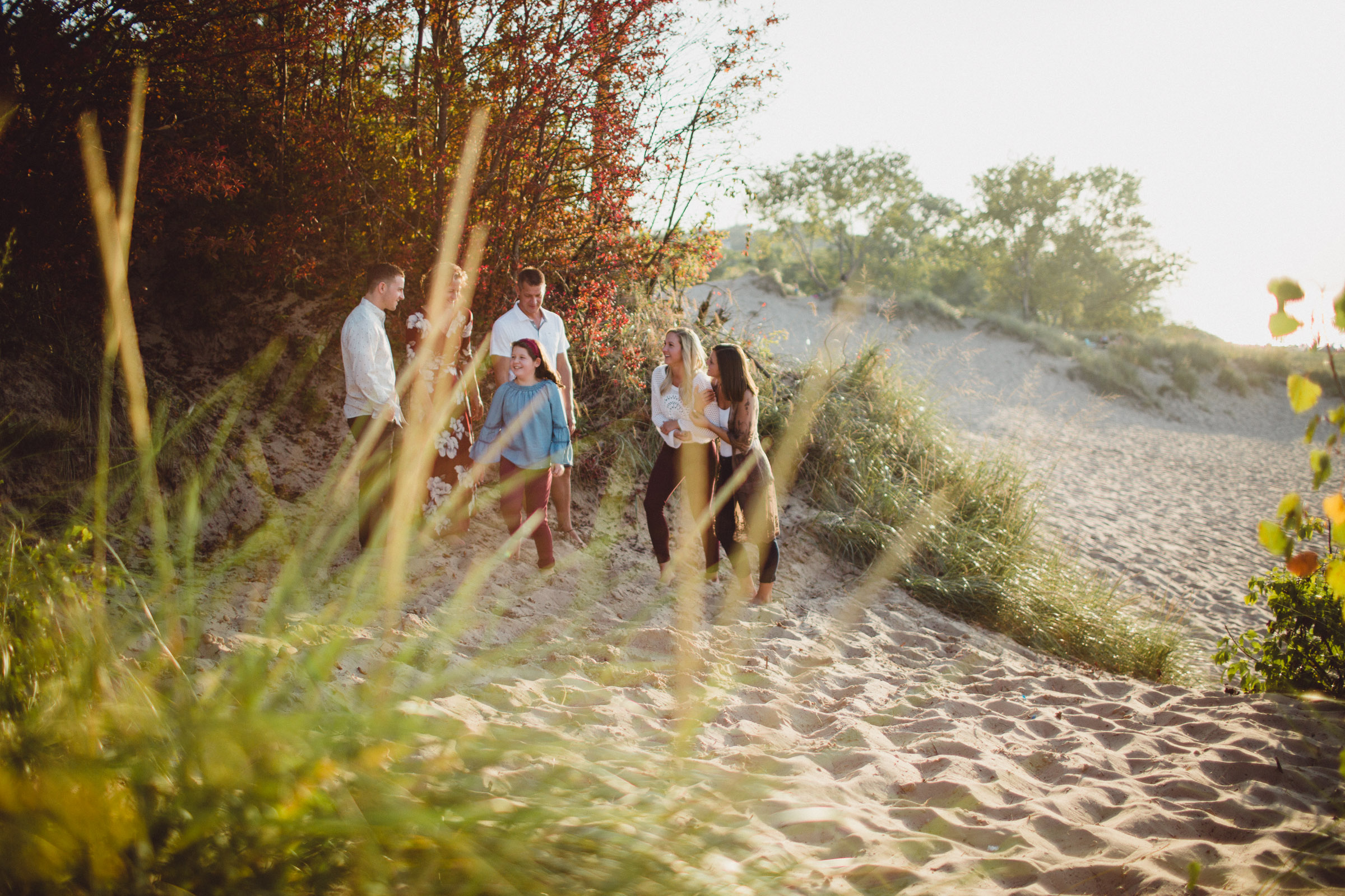 family connecting and interacting on beach, image shot through leaves