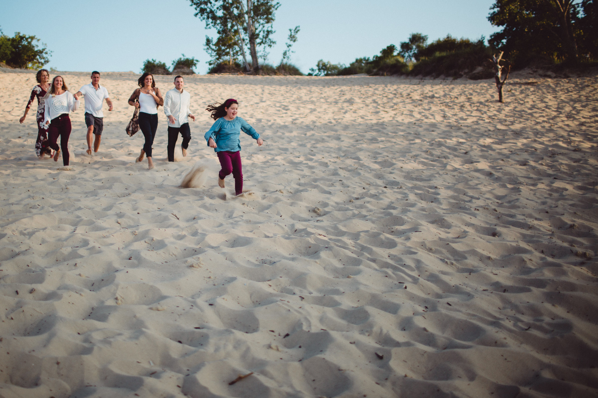 family running down a sand dune hill 