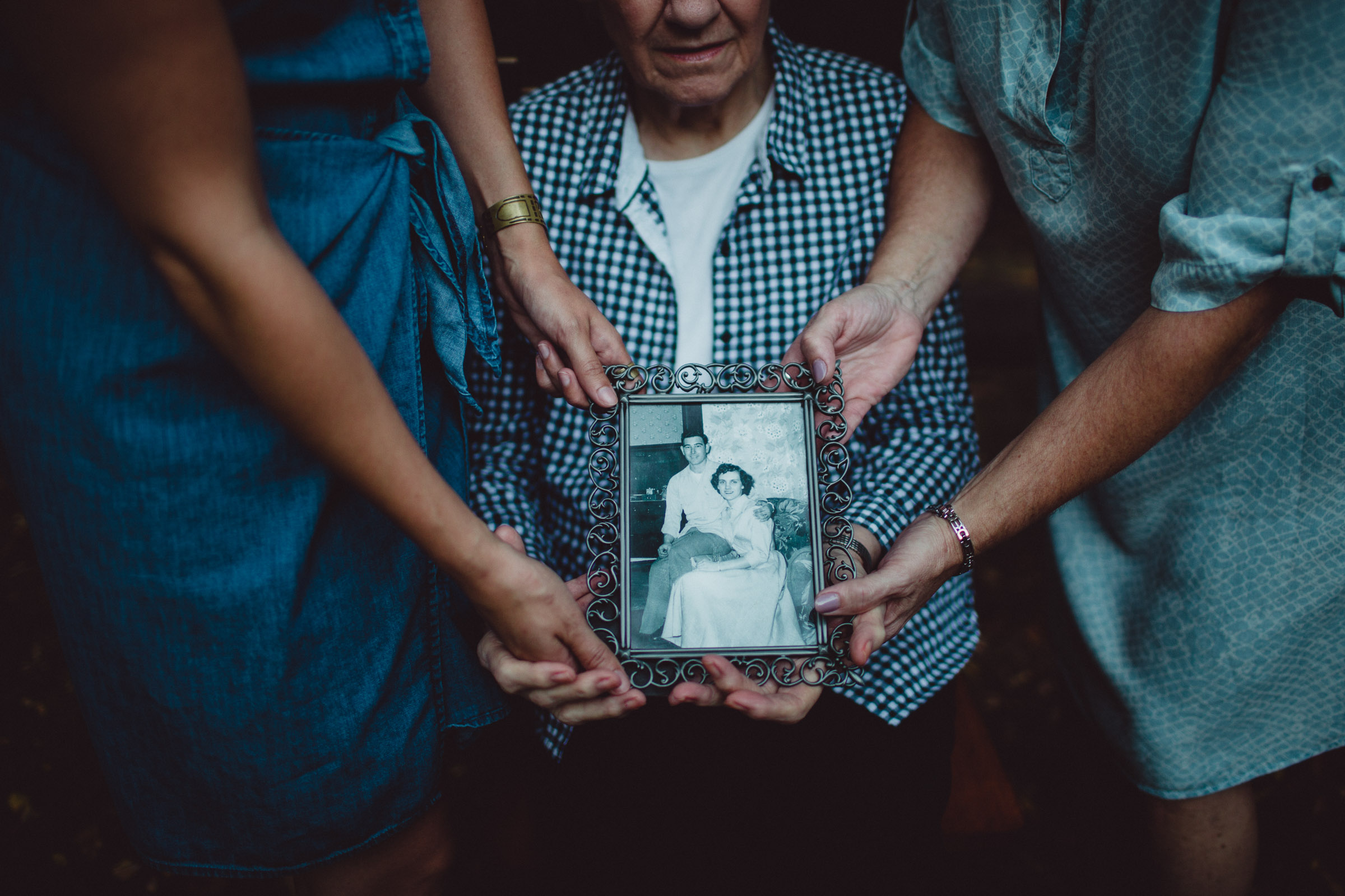 3 generations of women holding a frame of their loved one 