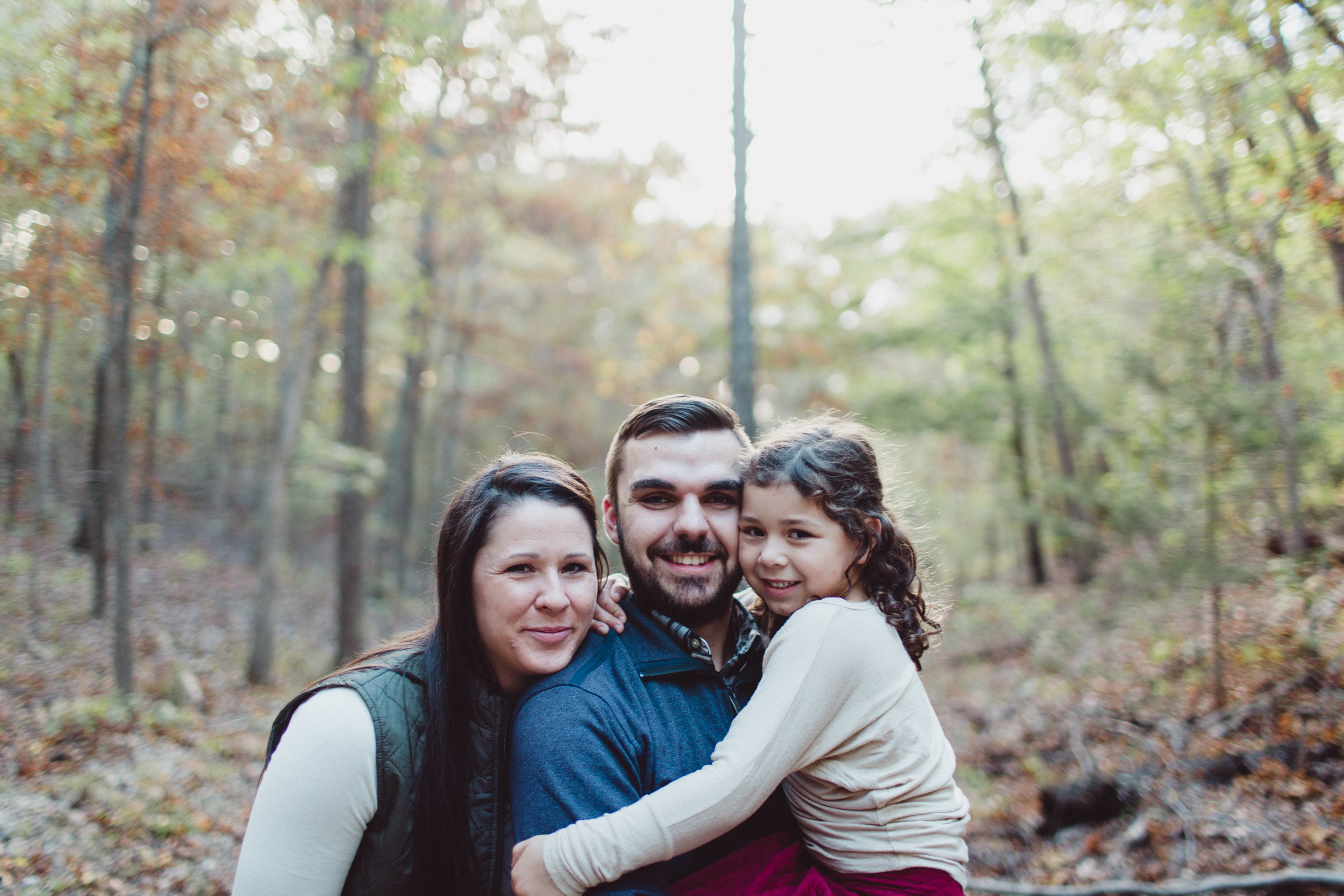 family snuggling together in woods 