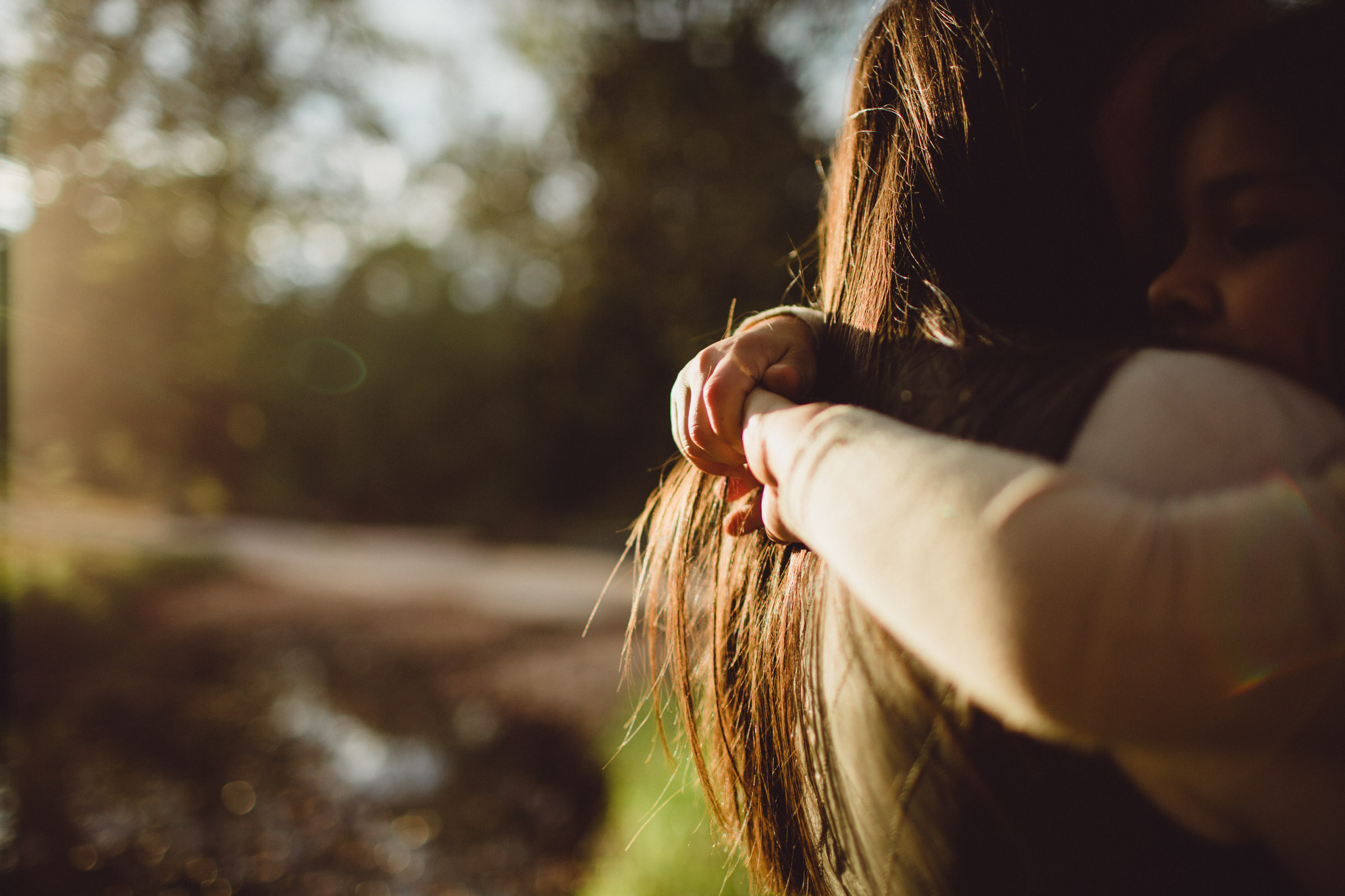 detail image of hands snuggles around mom's neck 