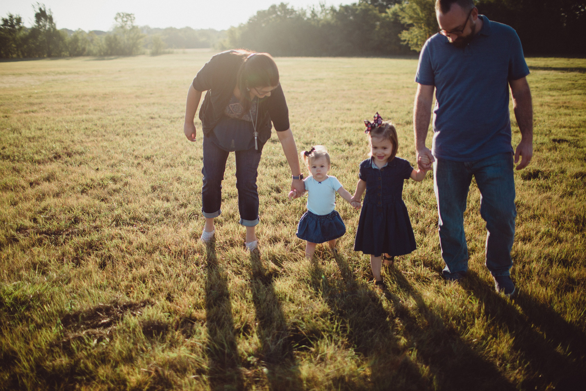 Family holding hands, sunrise backlit 