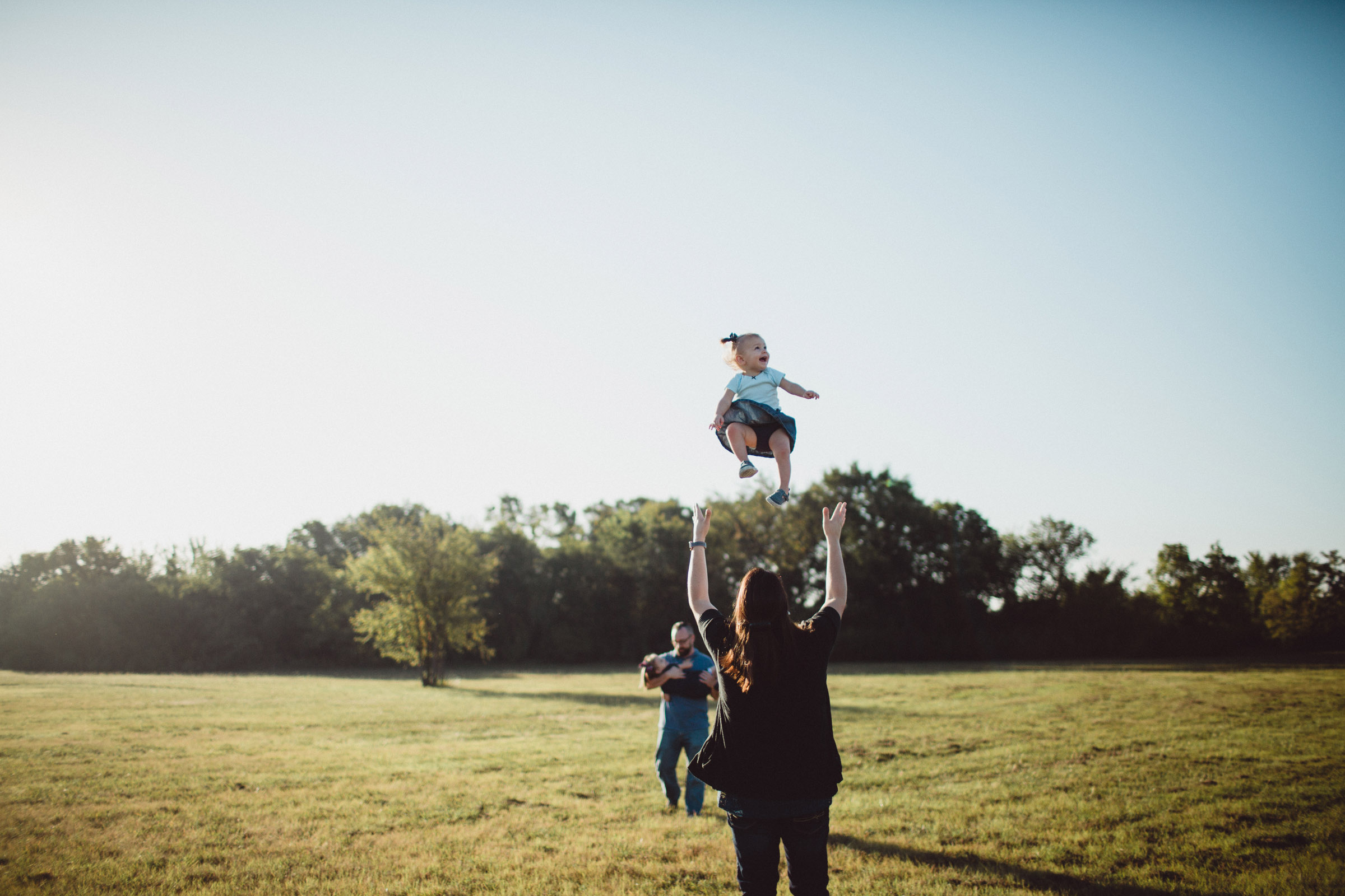 image of daughter joyfully being thrown into air by mother 