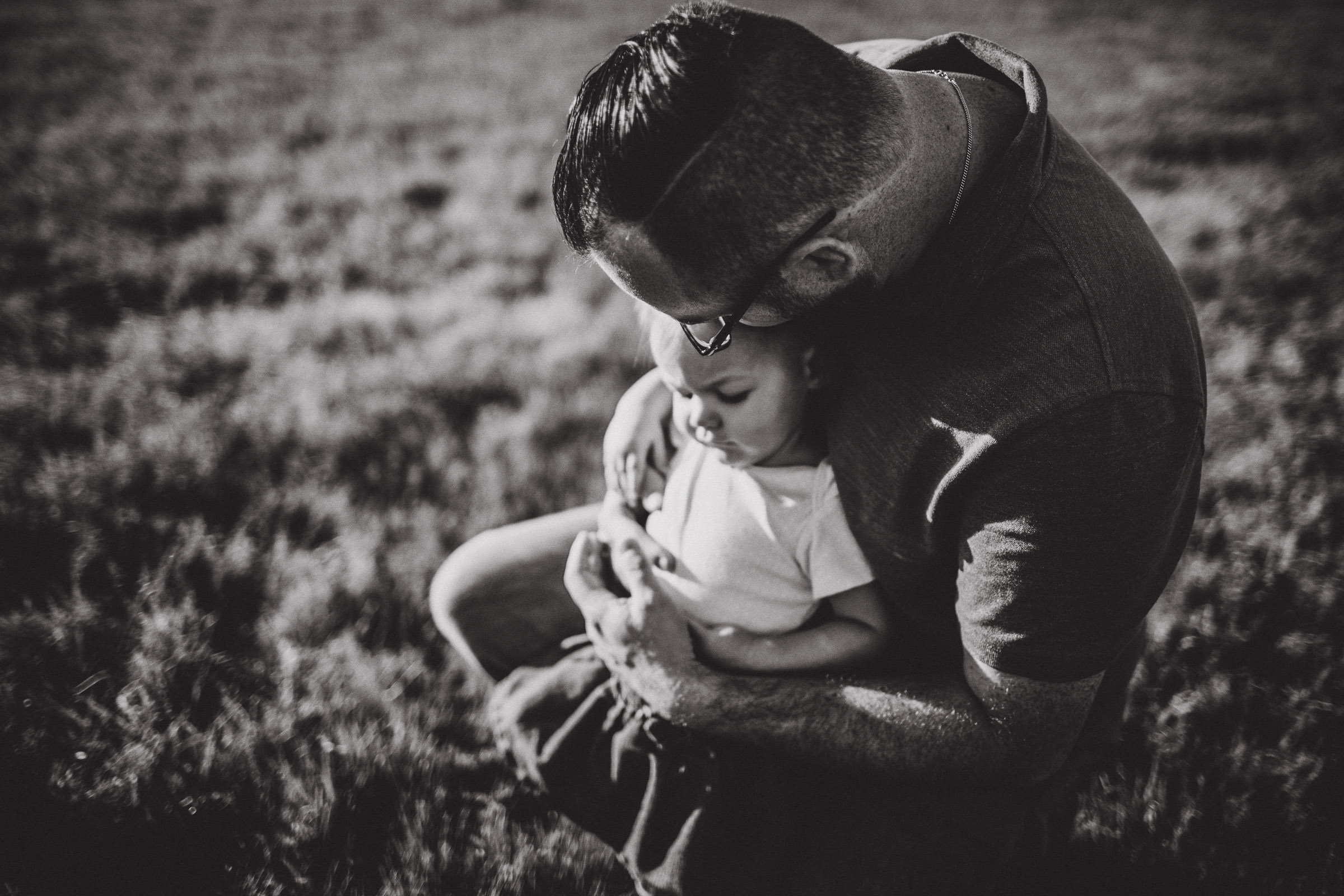 Black and white image of dad cradling his baby girl in his arms 
