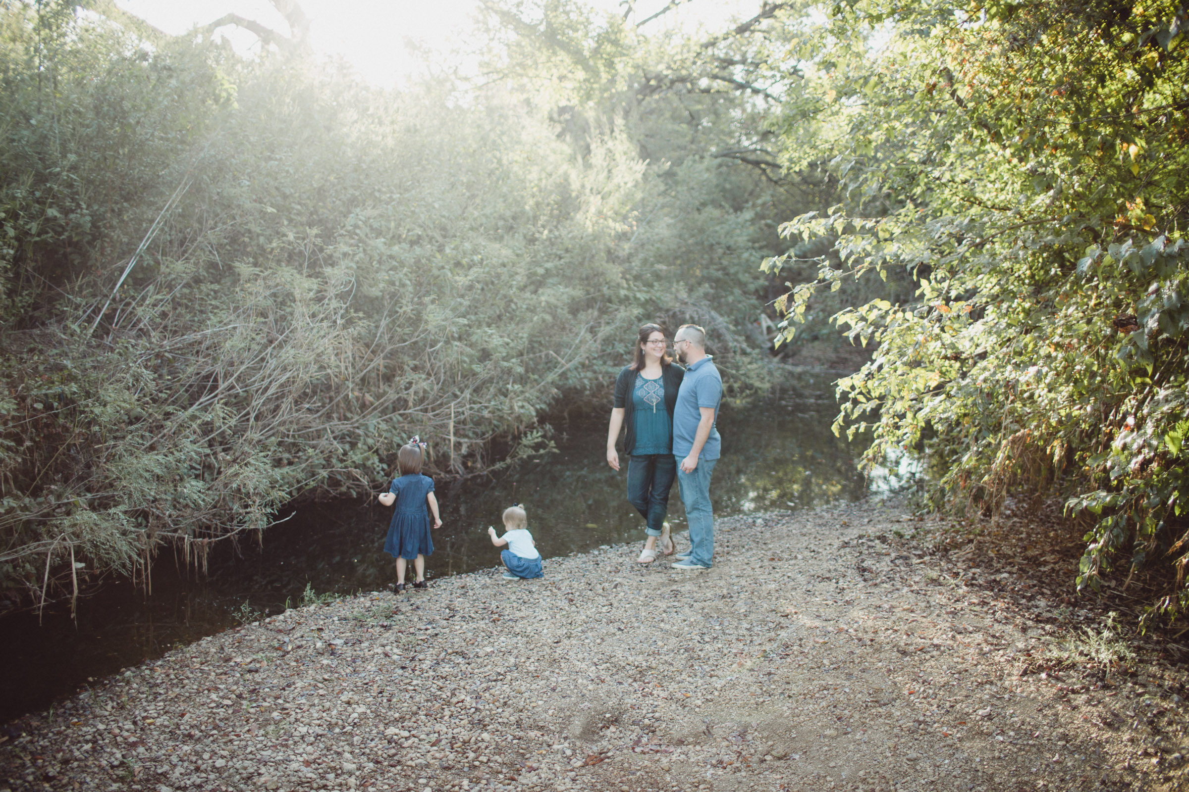 Image of family beside creek waters with light streaming in 