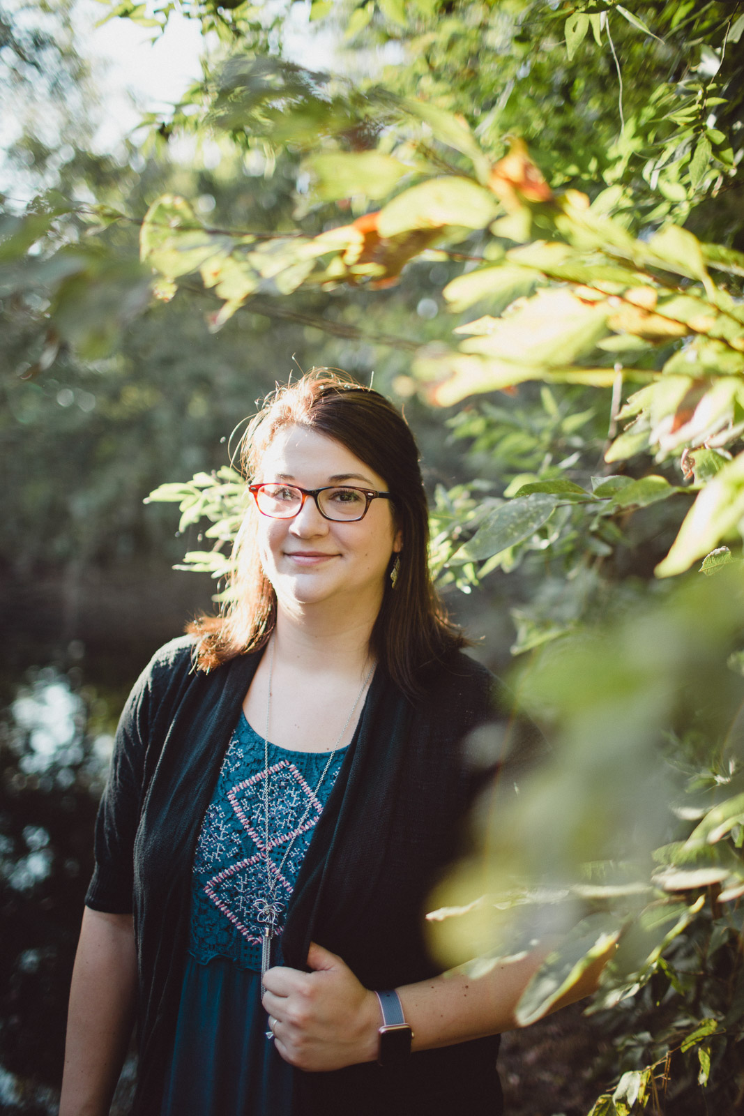 Portrait of woman, layered through leaves with sun flare beaming in 