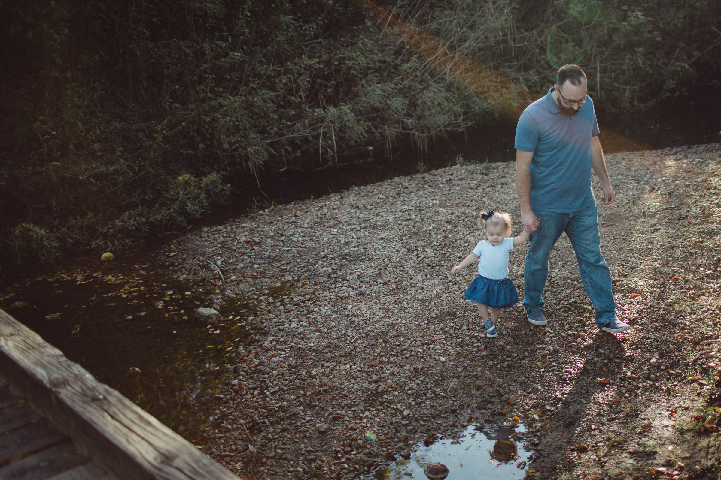 Father and daughter walking together beside creek 