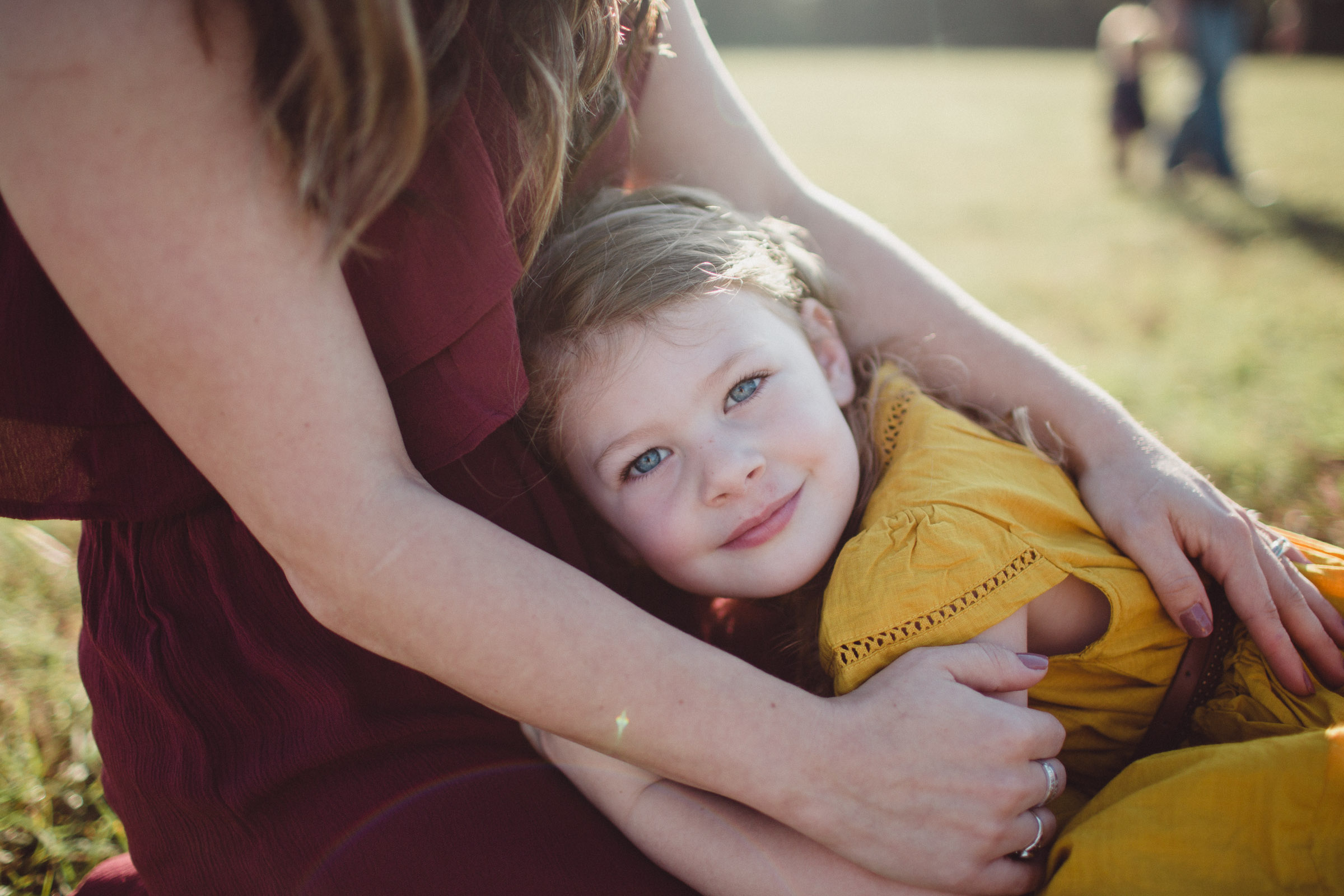 daughter lying on mothers lap, cradled into her arms 