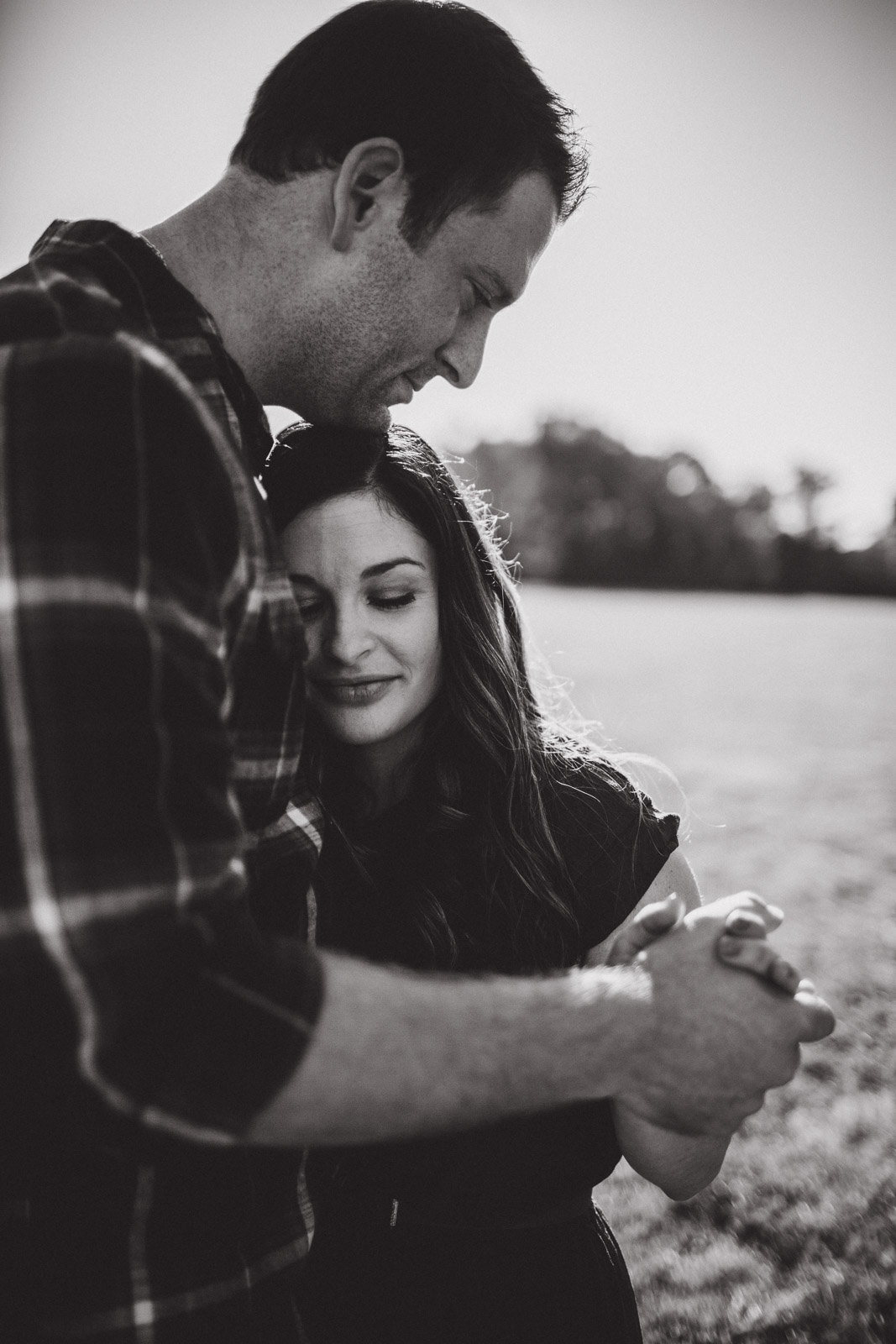 black and white portrait of wife resting within her husbands arms 