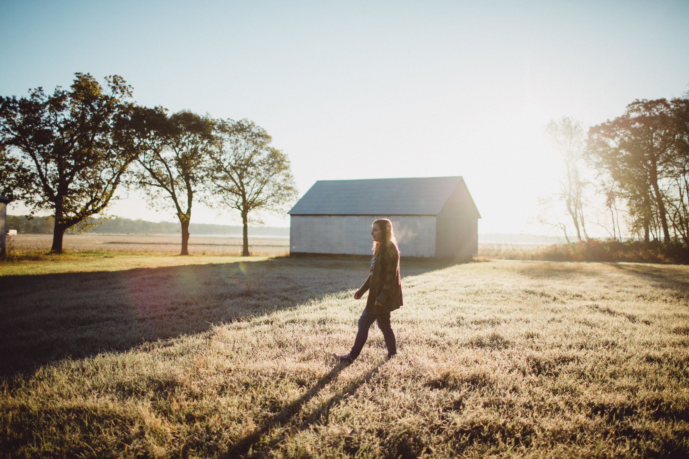 Mother walking across field, in dreamy morning light 