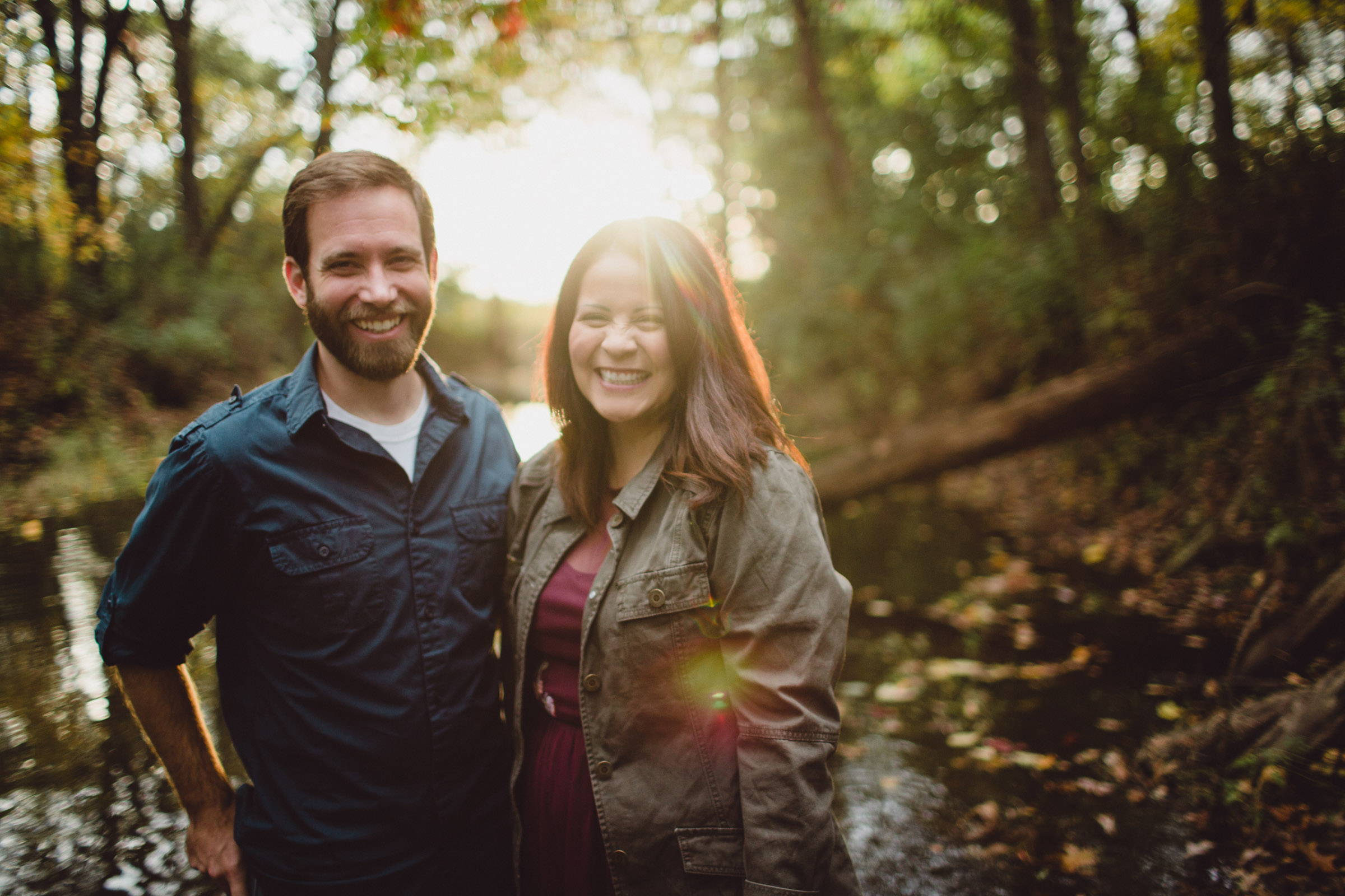 couple smiling with light flares in creek water 