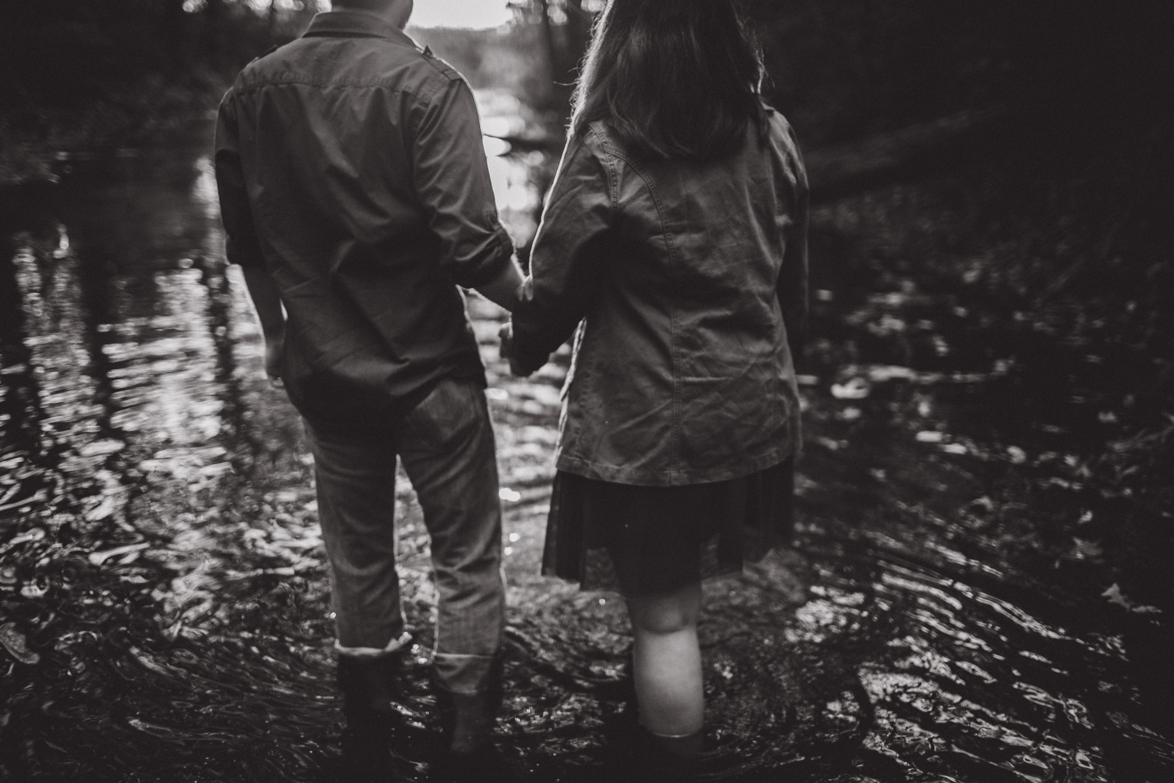 couple walking through water in creek, black and white portrait 