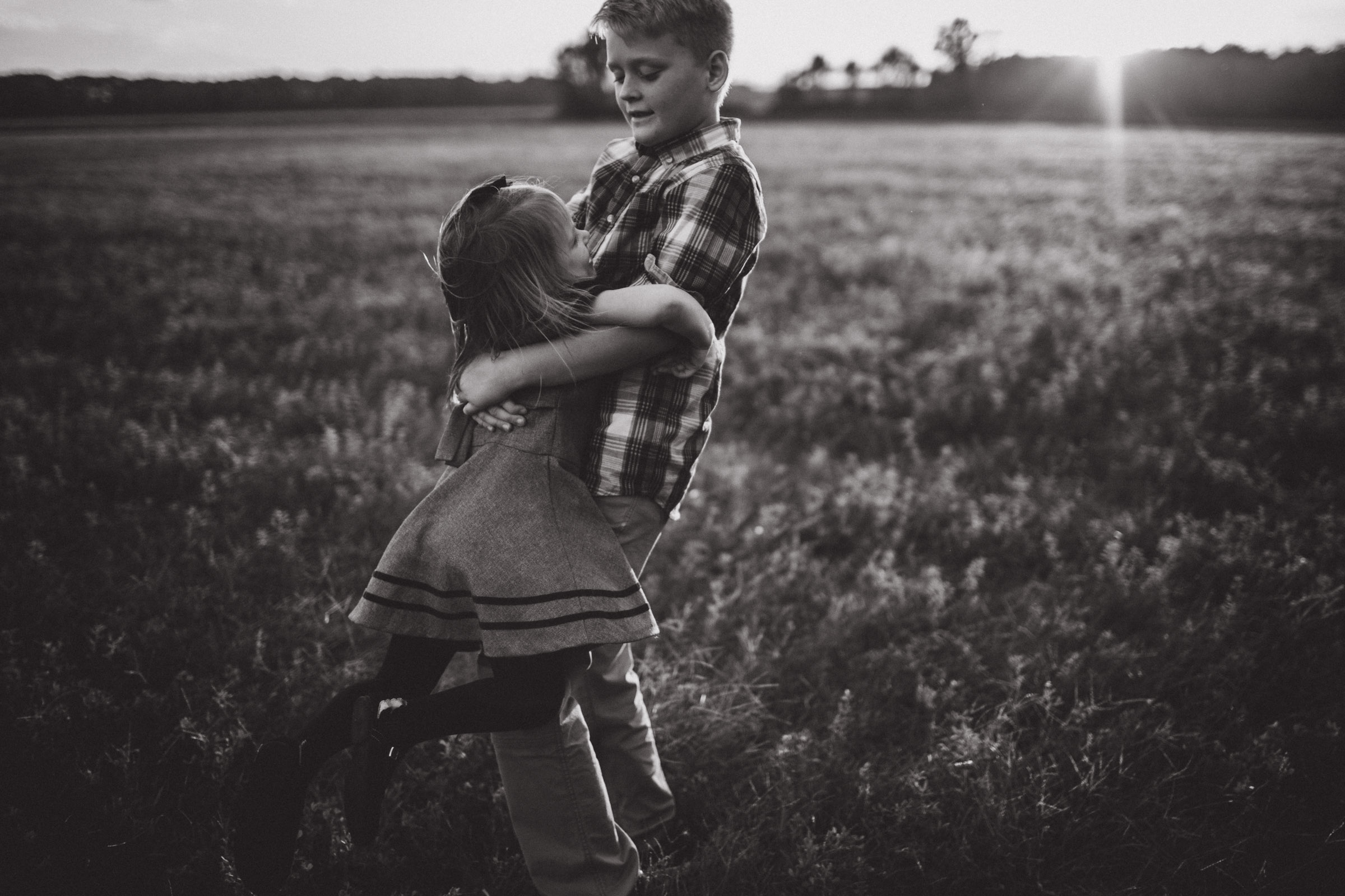 brother spinning younger sister in field 