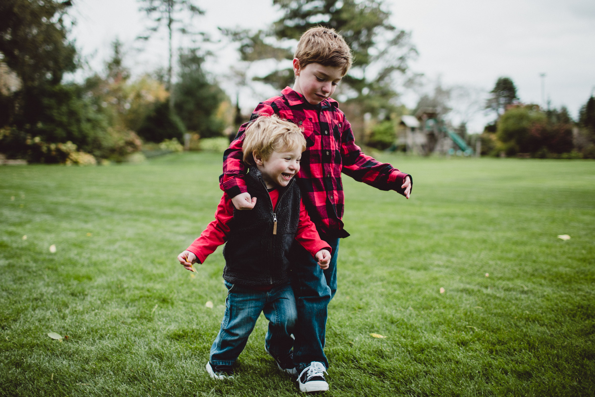 boys walking arm in arm together through field 