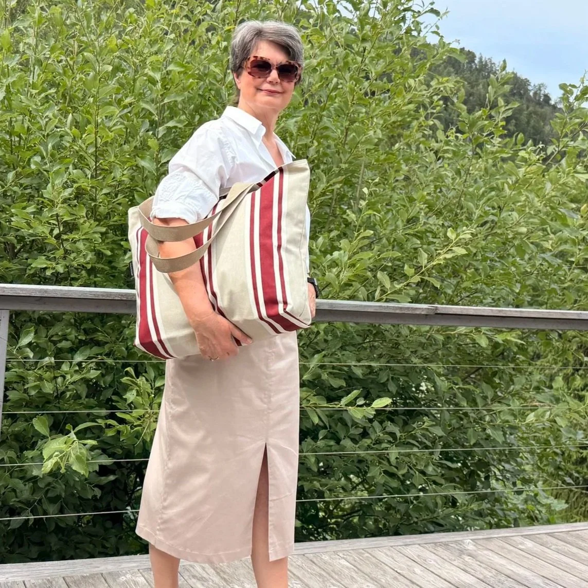 Model carrying an extra large 55x42x14 cm striped canvas tote bag to show its travel size.