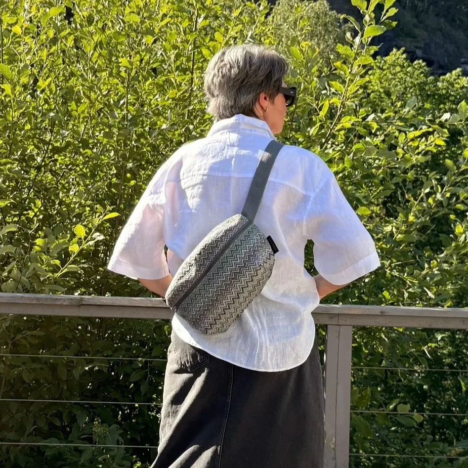 Side profile view of a model carrying the adjustable blue-grey-green Gobelin bag on her back as a crossbody.