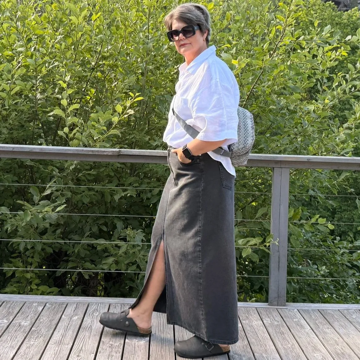 Woman with midi denim skirt, white shirt wearing the Capri sling on her back.