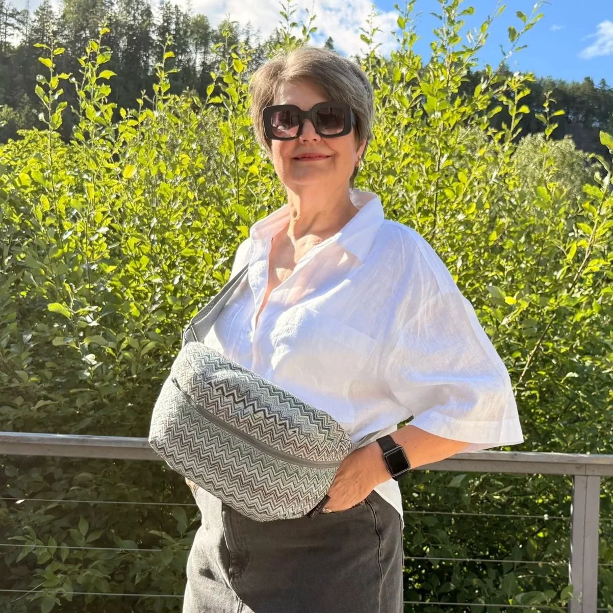 Cloes uo of model wearing a 32x18x11 cm zig-zag tapestry bag as a high-chest sling to show a hands-free travel look.