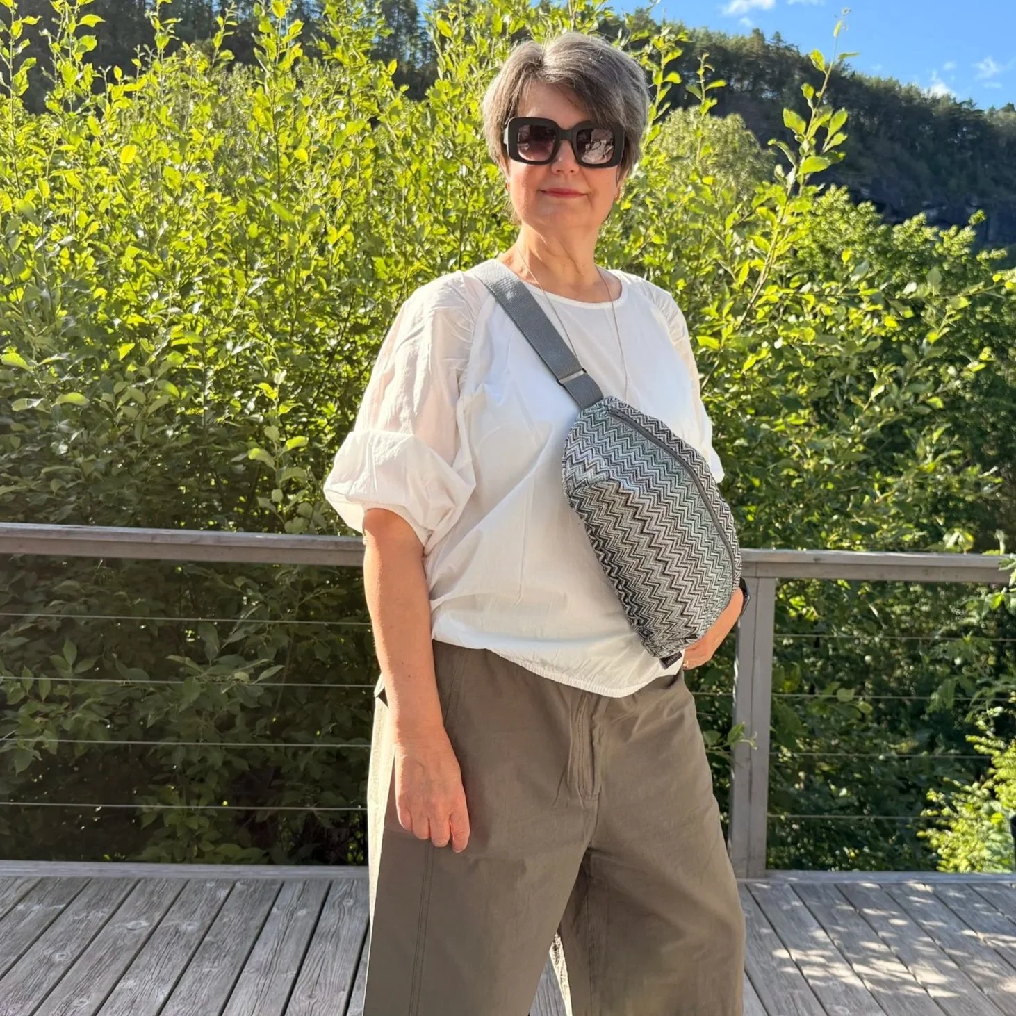 Frontview of woman wearing shorts and the Fjord crossbody sling crossed over her body.