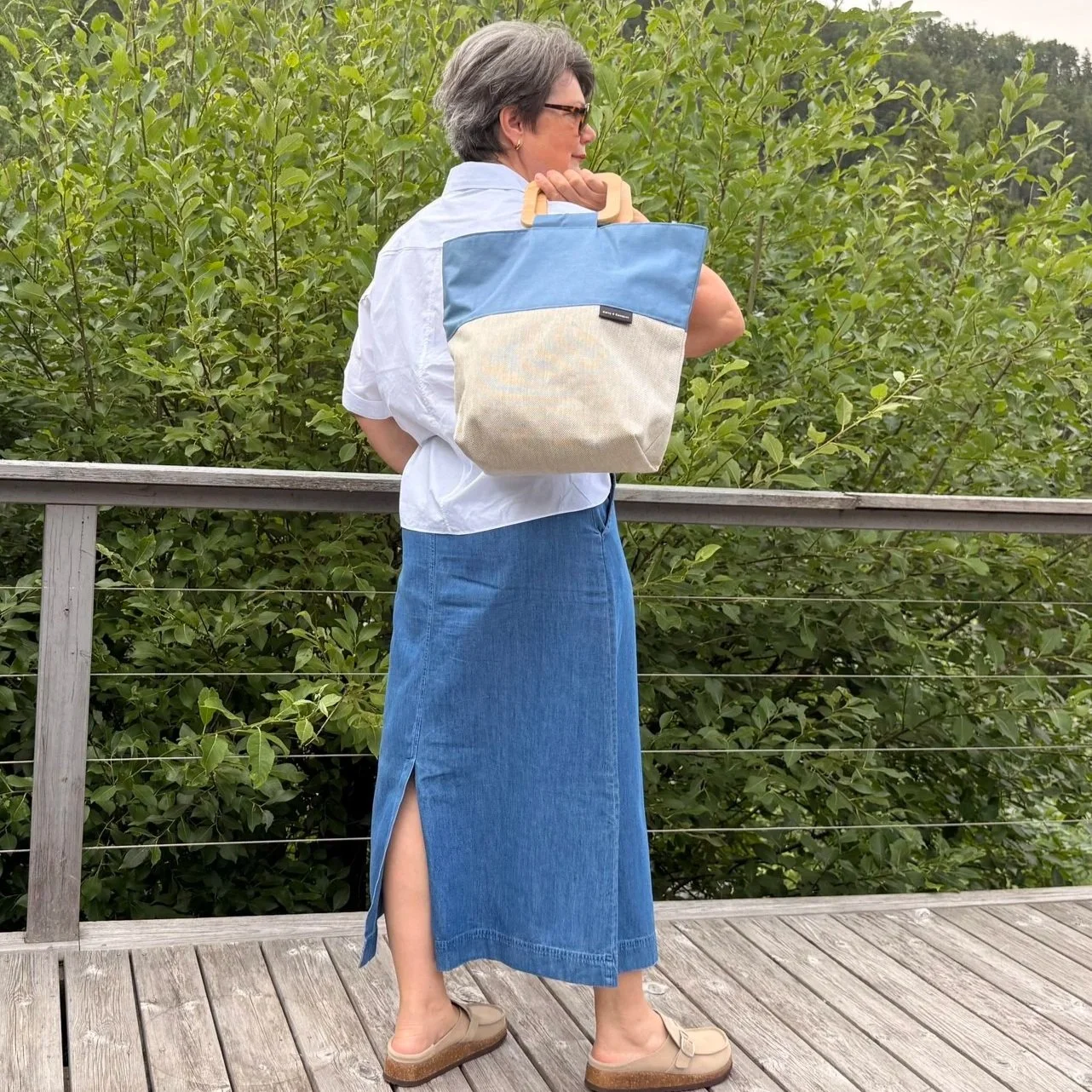 Modell wearing andmade beige canvas tote bag with dusty blue accents and geometric square wooden handles.