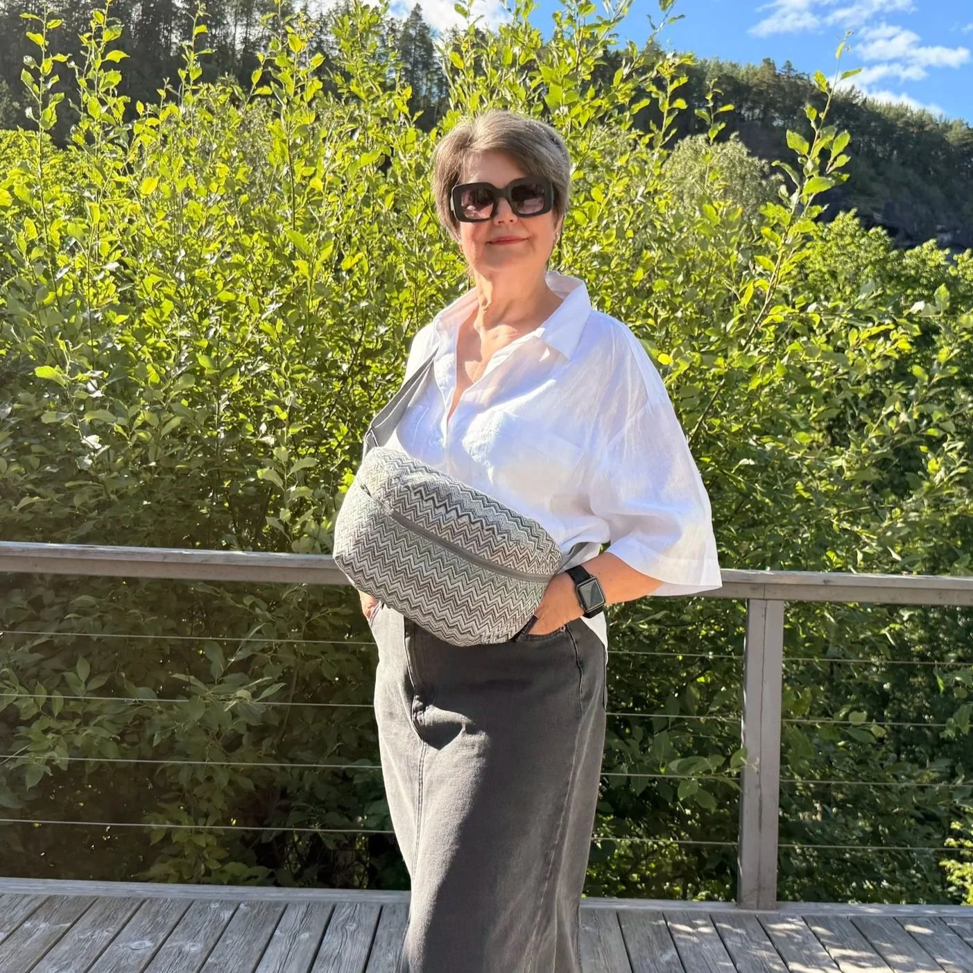 Model wearing a 32x18x11 cm zig-zag tapestry bag as a high-chest sling to show a hands-free travel look.