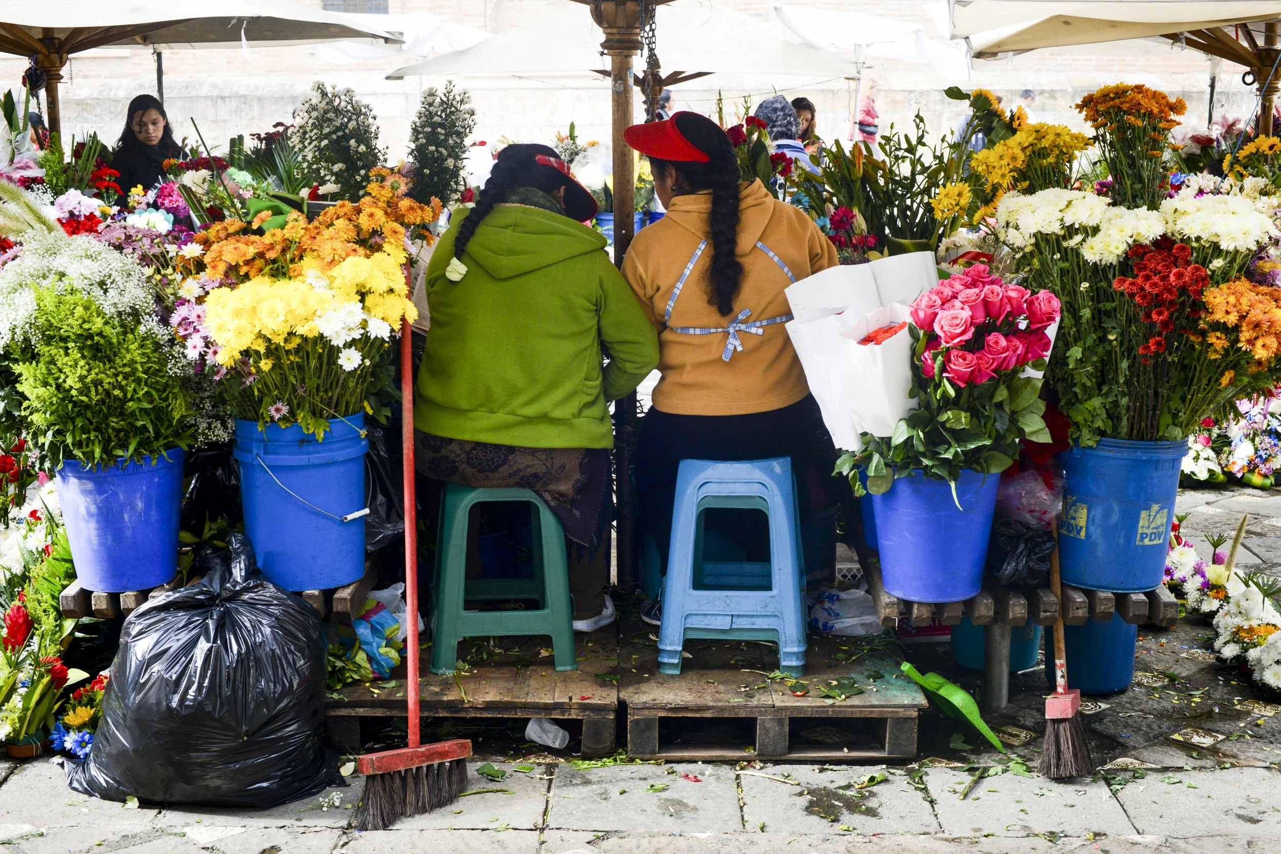  Flower merchants share a private conversation at their street mercantile - Cuenca, Ecuador. 