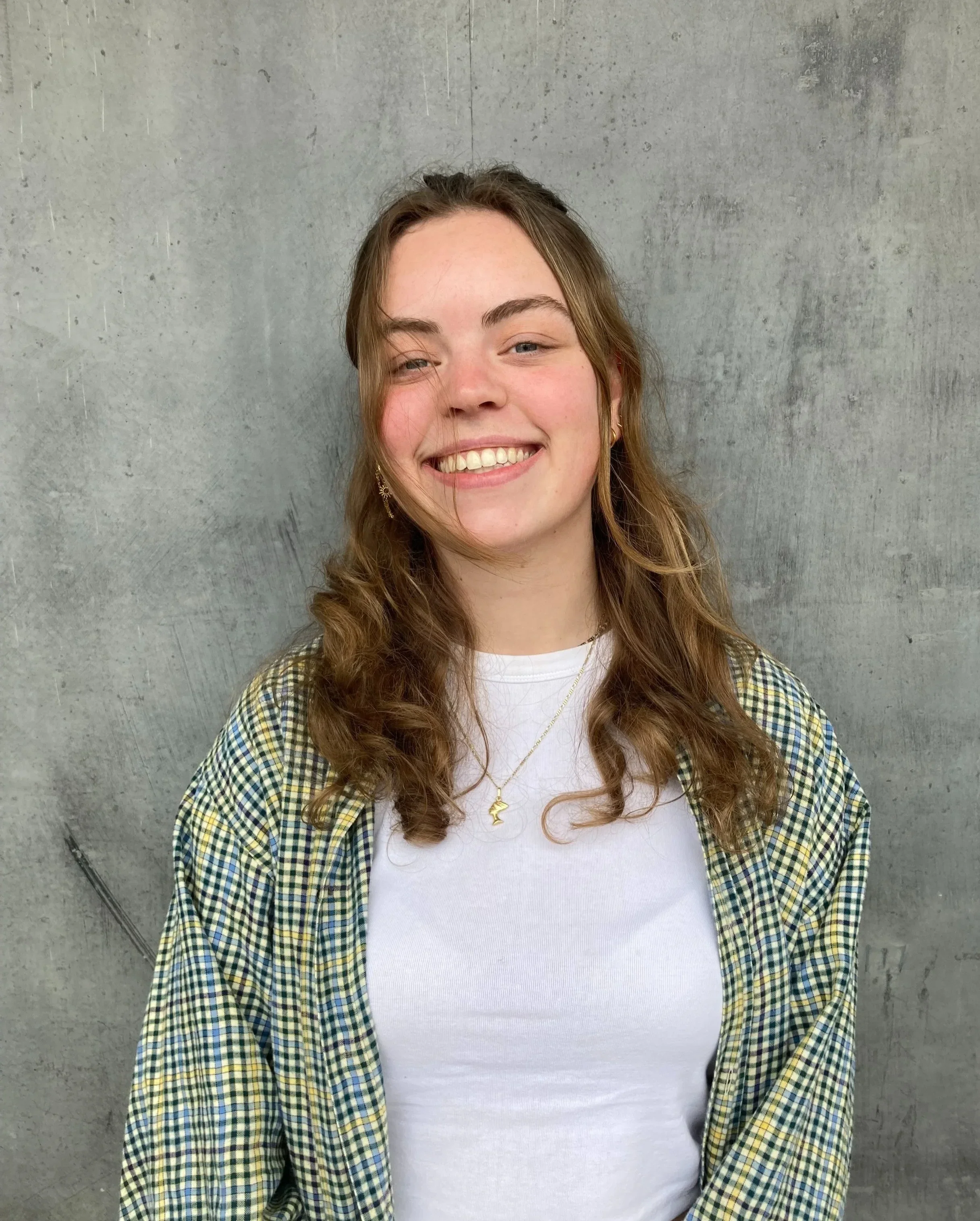 Jade is een jonge psychologe, die enthousiast lacht voor een grijze muur. Ze draagt een witte t-short en een geruit hemd.