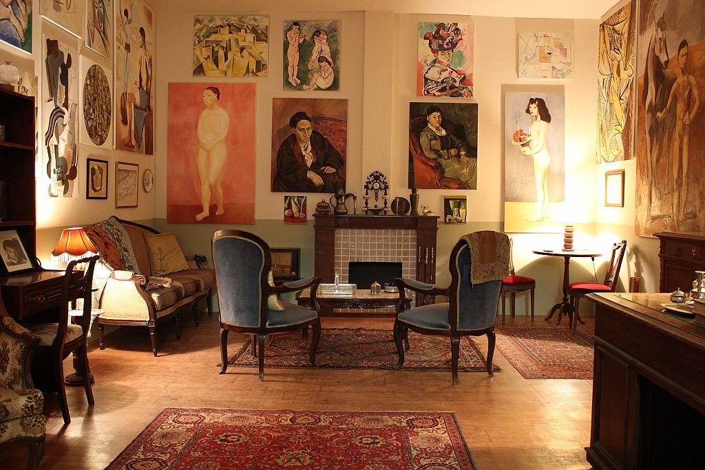 Recreation of Gertrude Stein's Paris salon at 27 rue de Fleurus, its walls covered floor-to-ceiling with modernist paintings including works by Picasso and Cézanne.