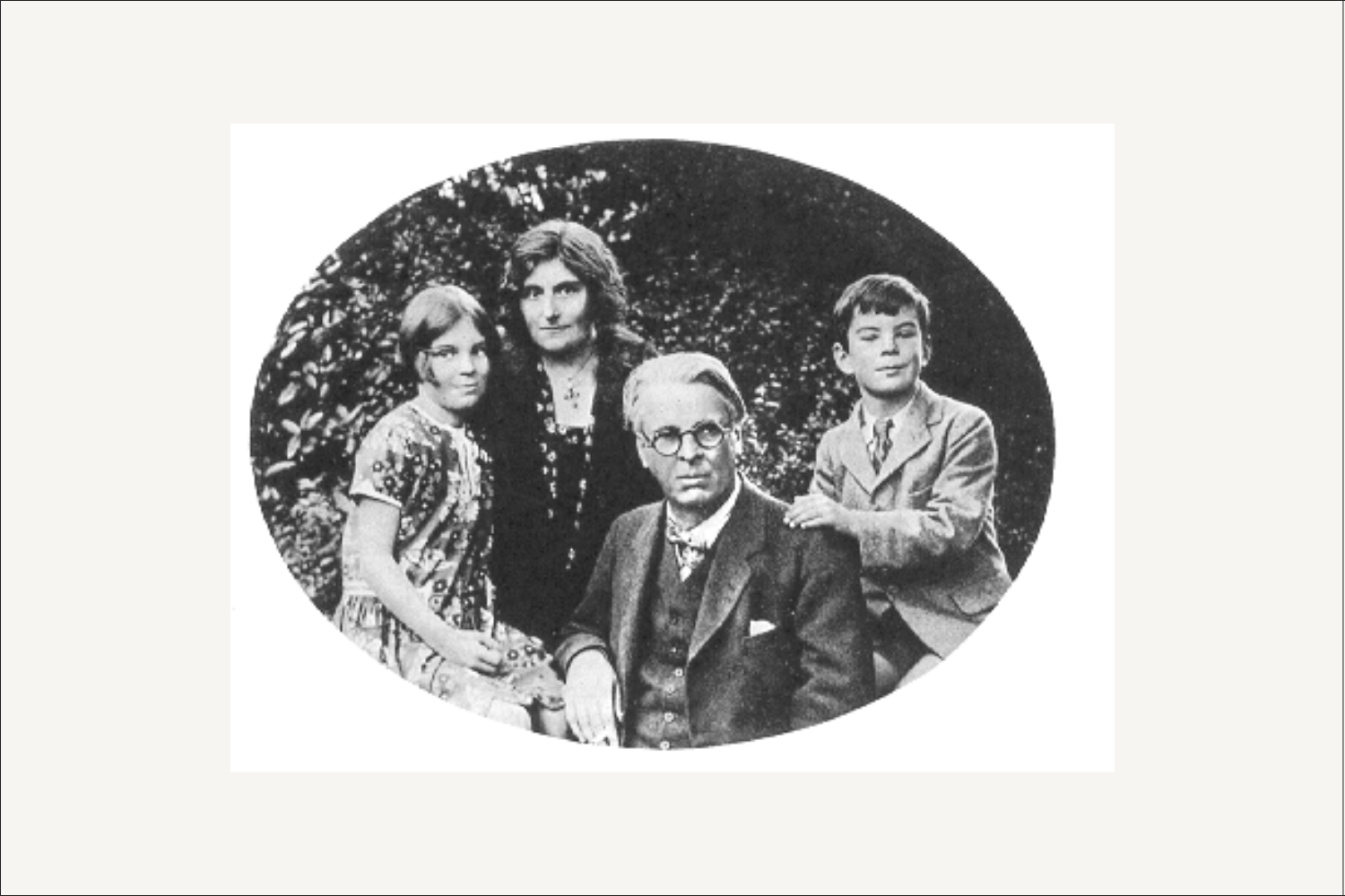 Black and white oval family portrait of W.B. Yeats seated with Georgie standing behind him, flanked by their two children.