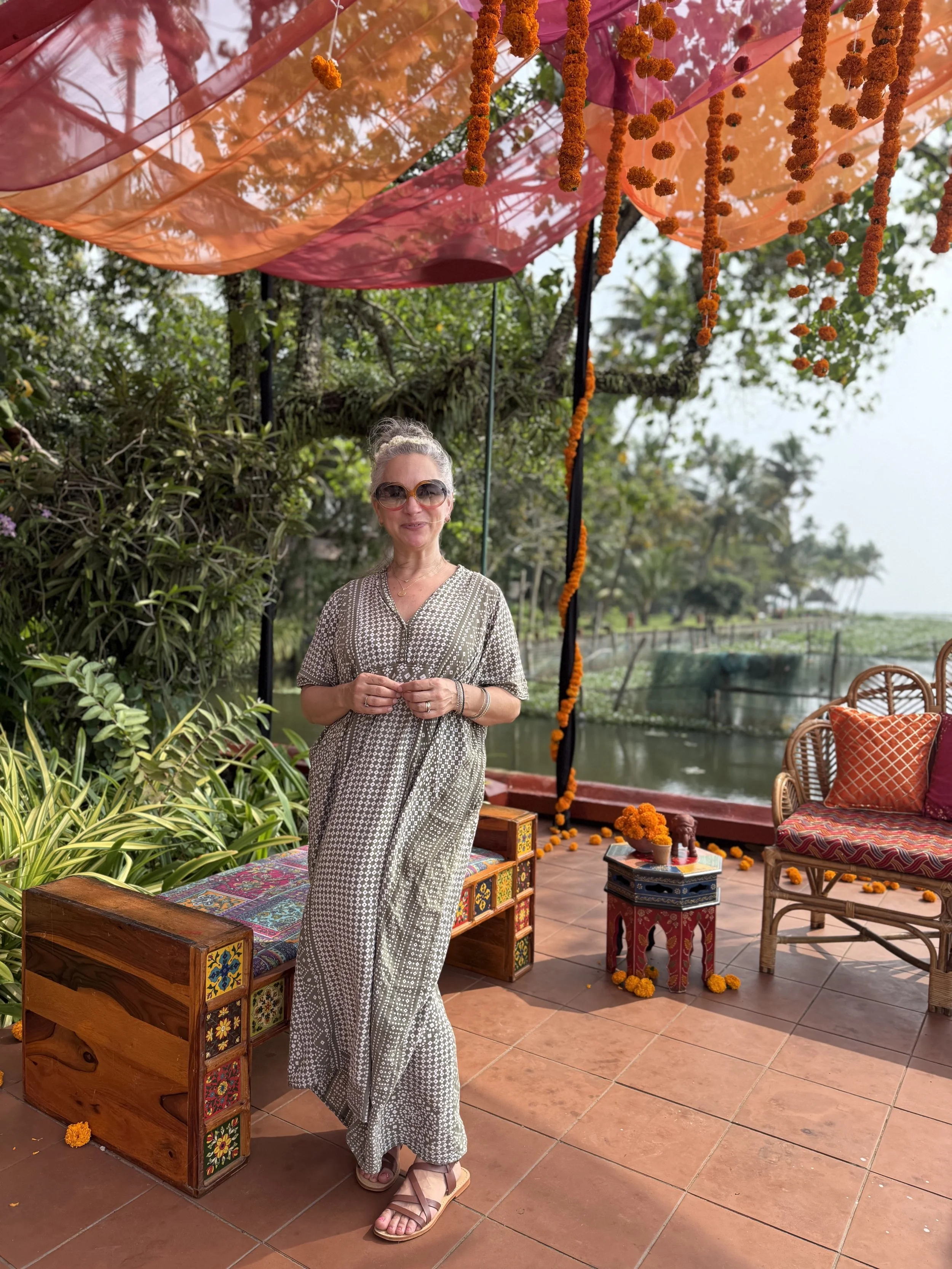 Woman standing on a tiled terrace decorated with marigold garlands and colorful fabric at a wedding venue in Kerala, India.