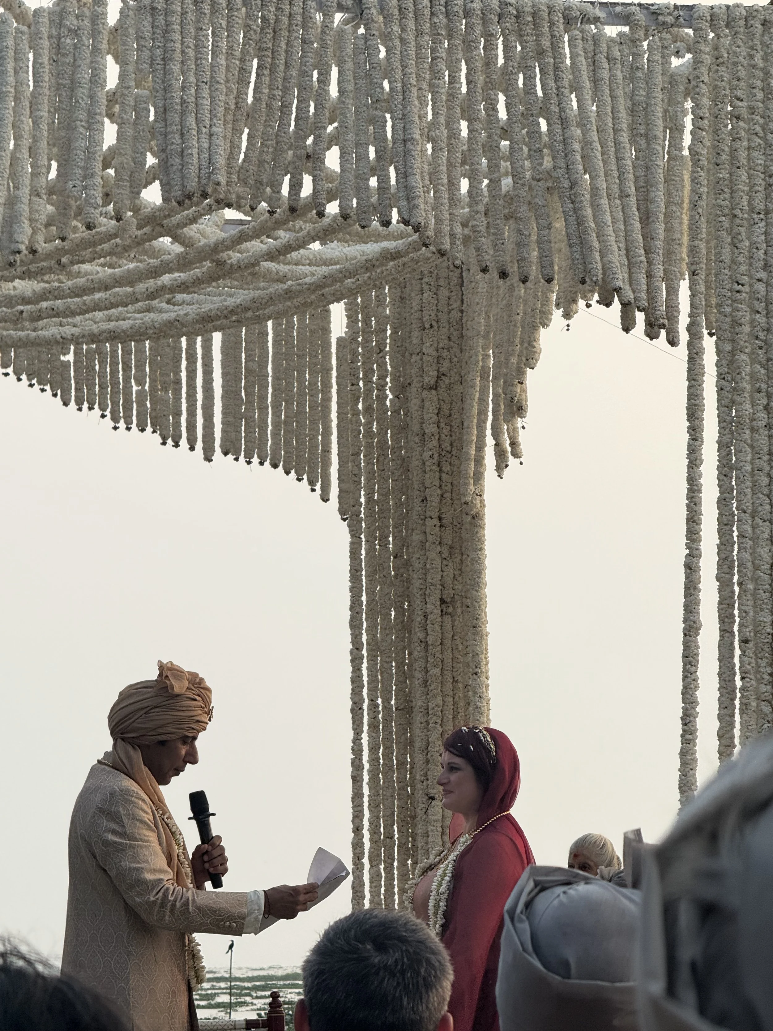 Wedding ceremony in Kerala with bride and groom standing beneath a canopy of hanging white flower garlands.